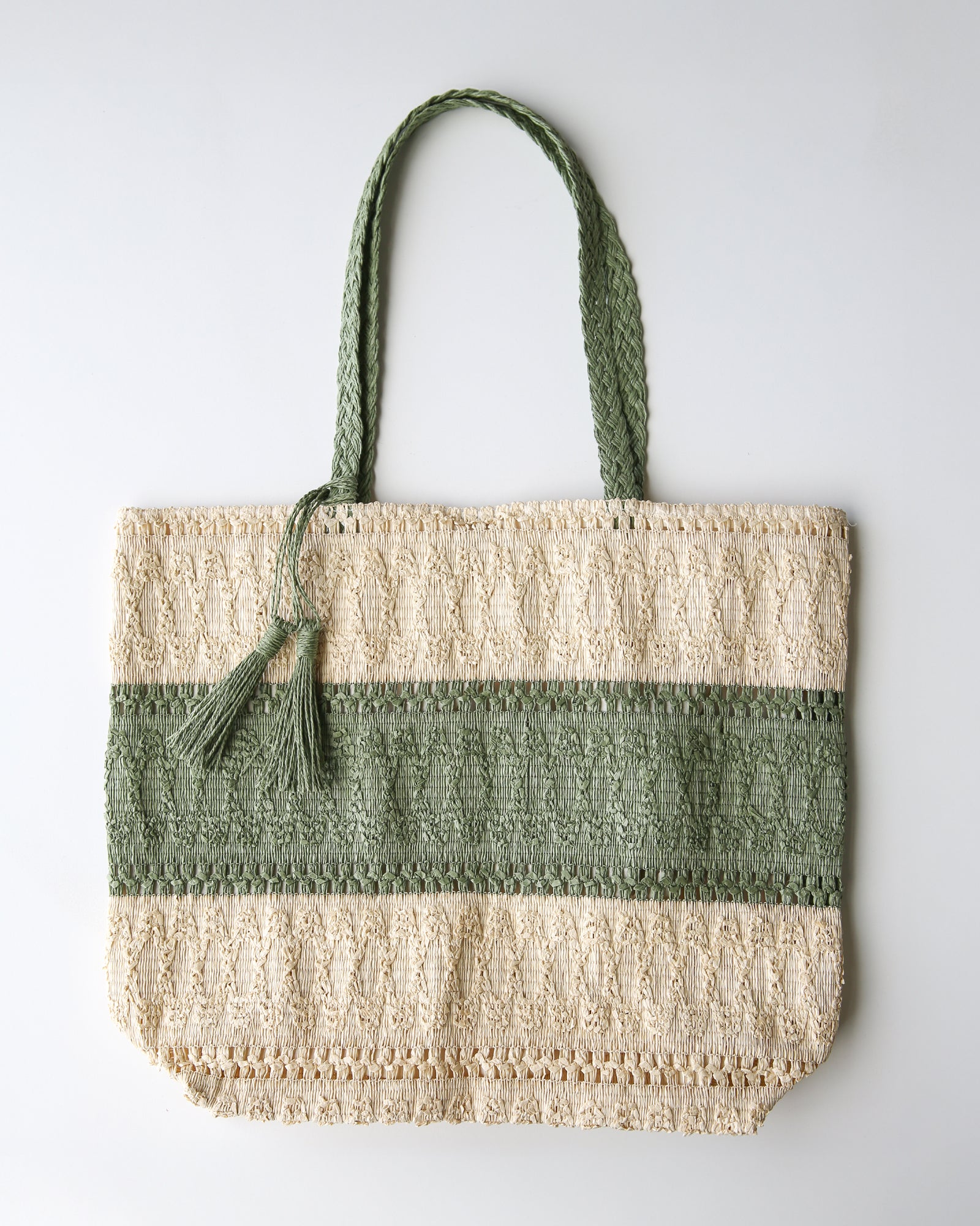 Green and beige woven tote bag with tassel on a white background