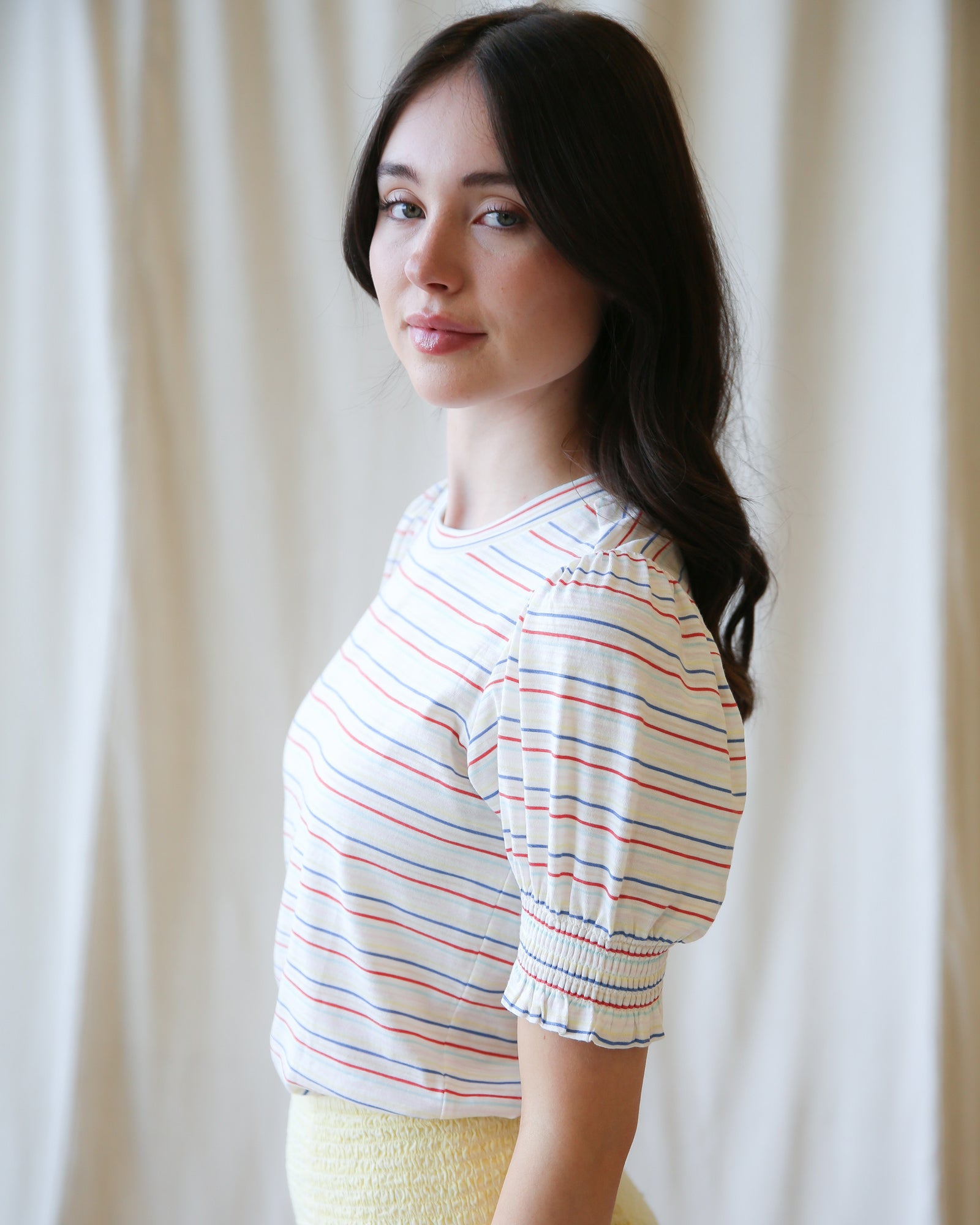 Woman wearing a striped shirt against a plain background