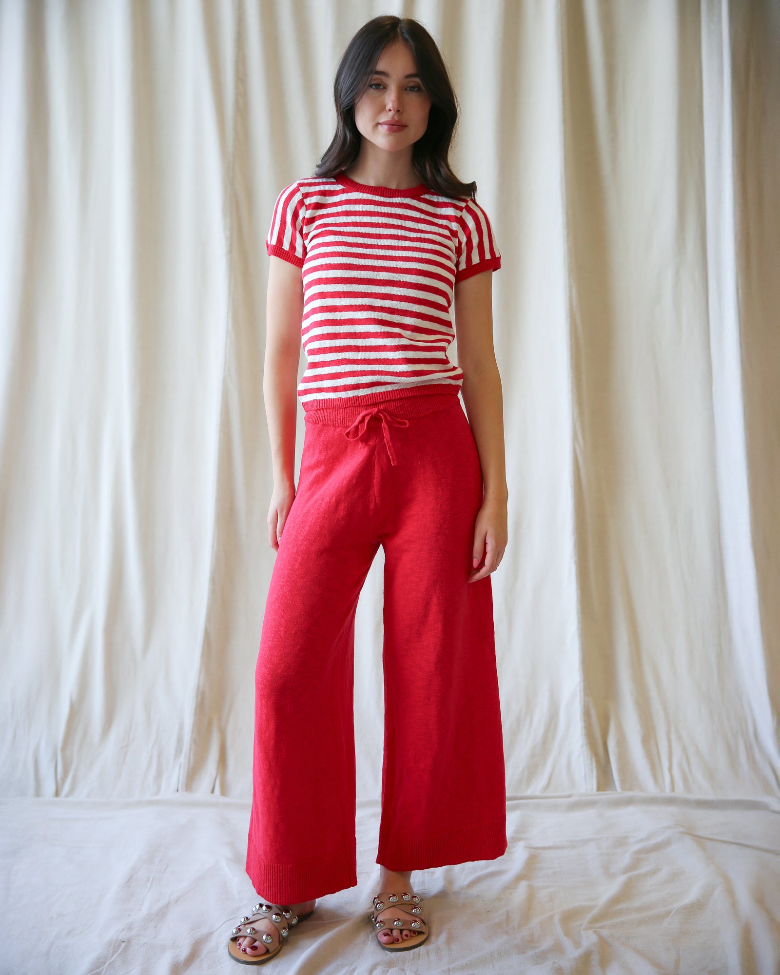 Woman wearing a red and white striped shirt and red pants against a plain background