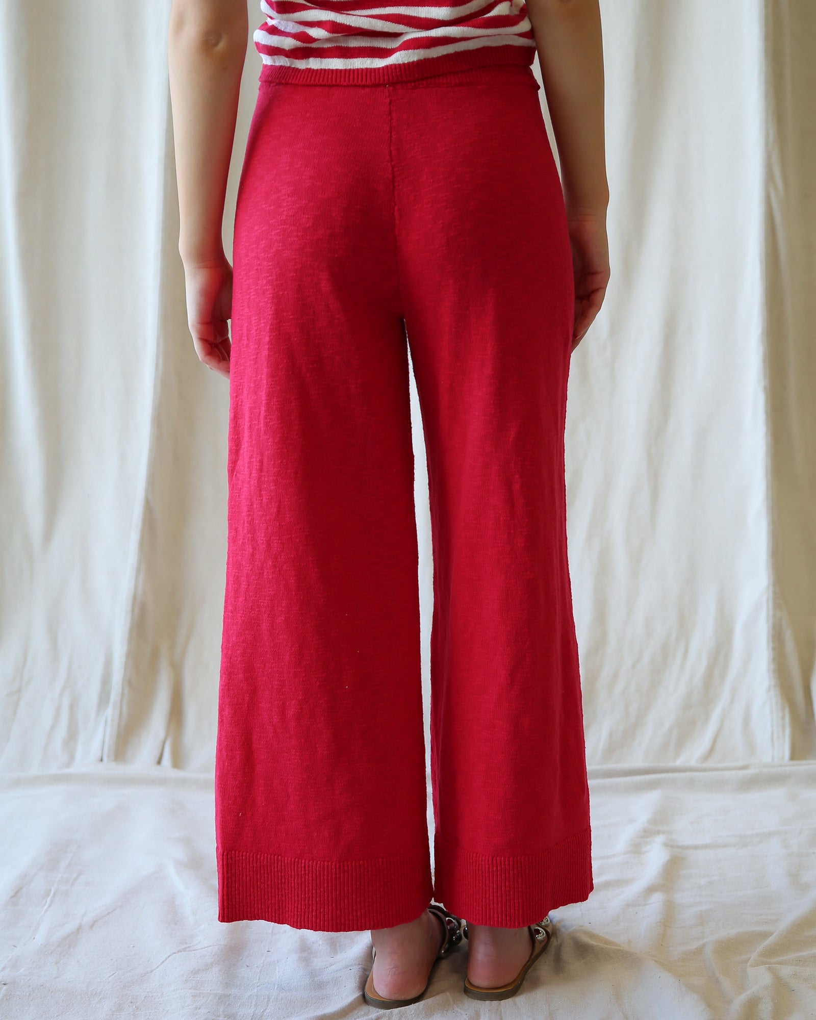 Person wearing red wide-leg pants and a striped shirt against a white background