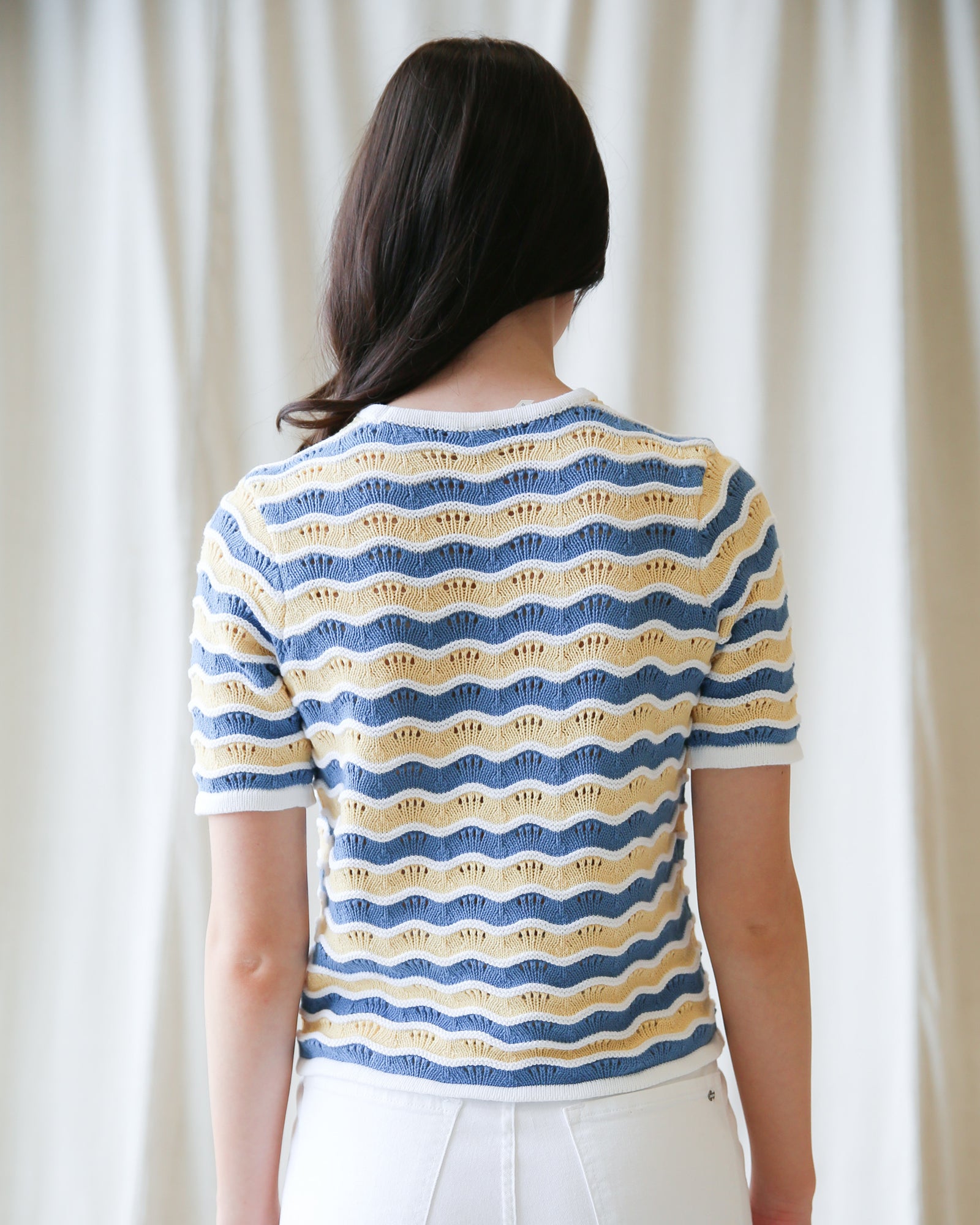 Person wearing a striped shirt with wavy pattern against a plain background