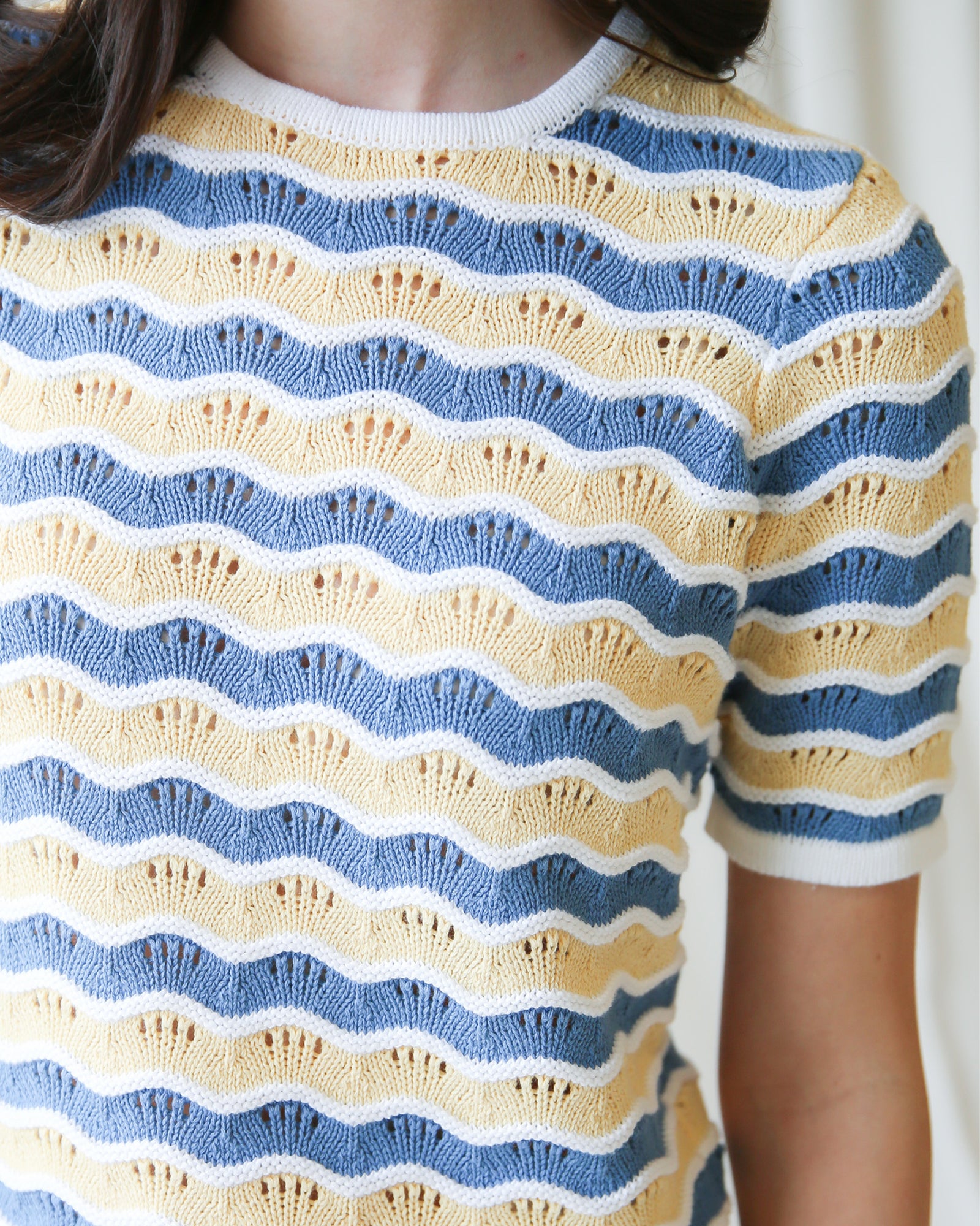 Close-up of a person wearing a blue and yellow striped sweater.