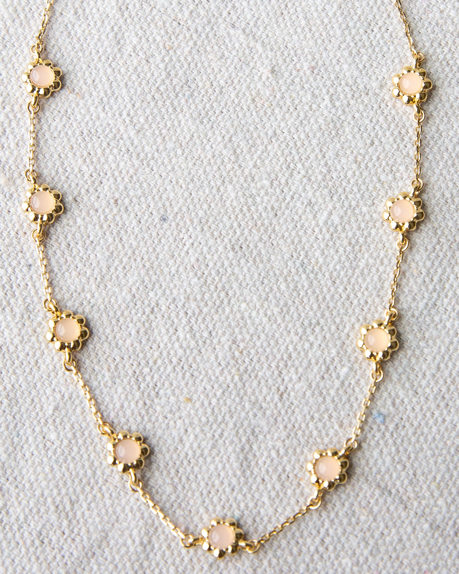Gold necklace with pink opal stones on a light gray background