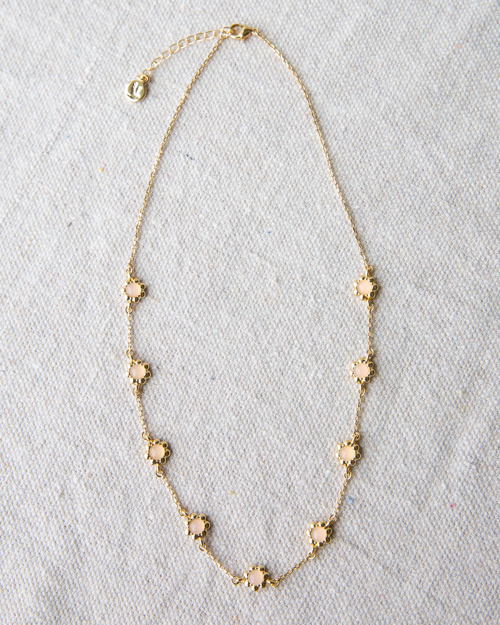Gold necklace with floral pendants on a light gray background