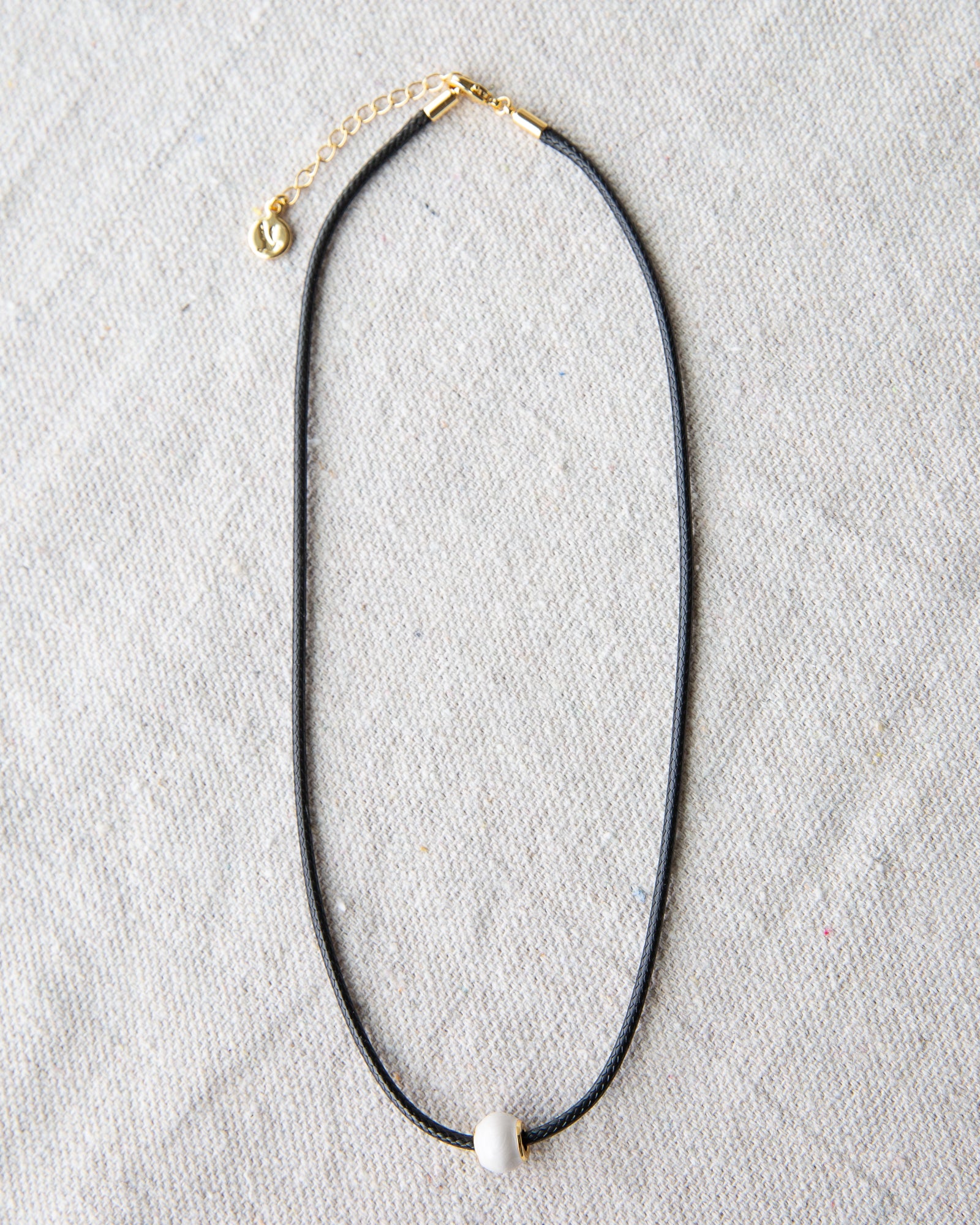 Black necklace with a gold chain on a gray background