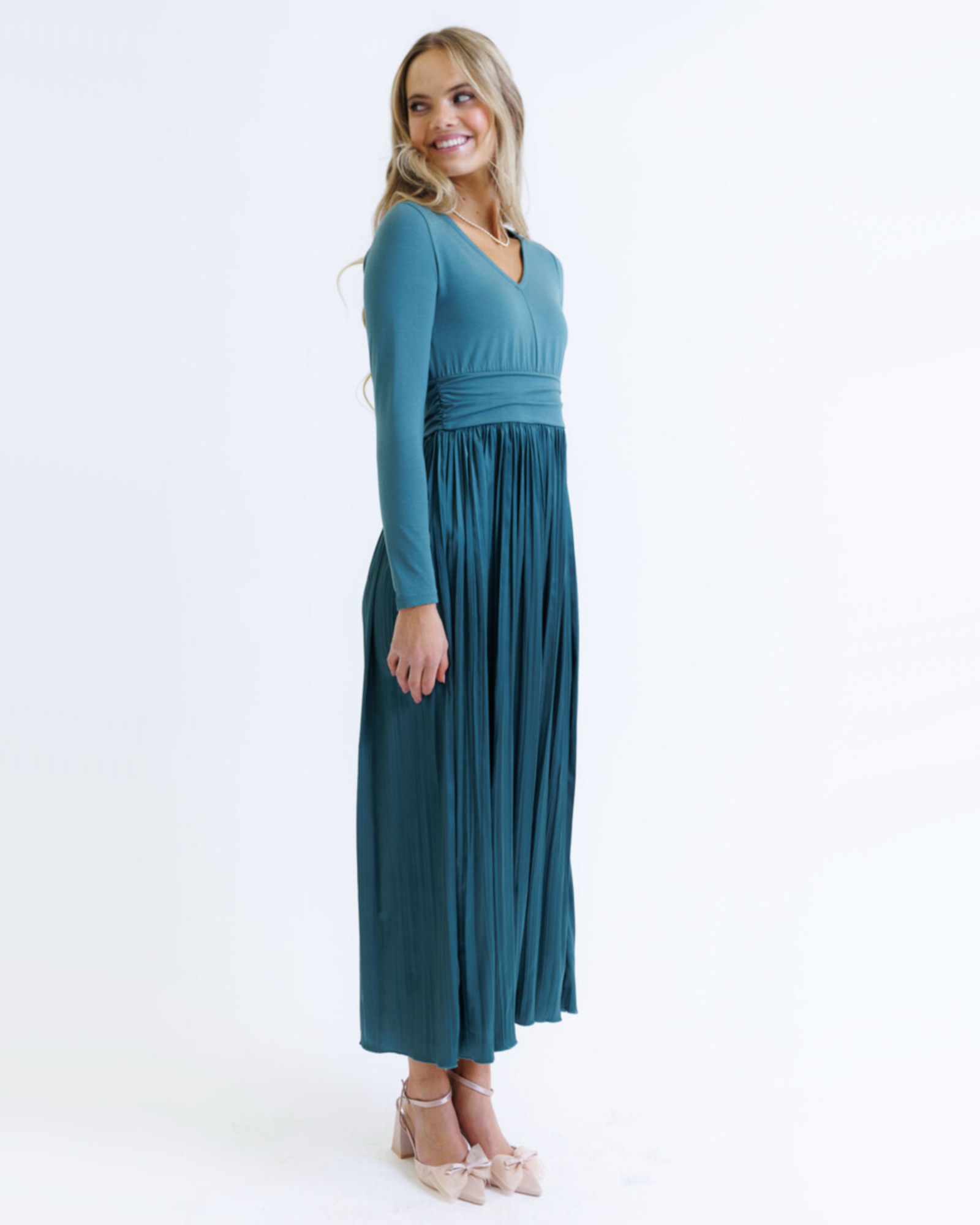 Woman wearing a teal long-sleeve dress on a white background
