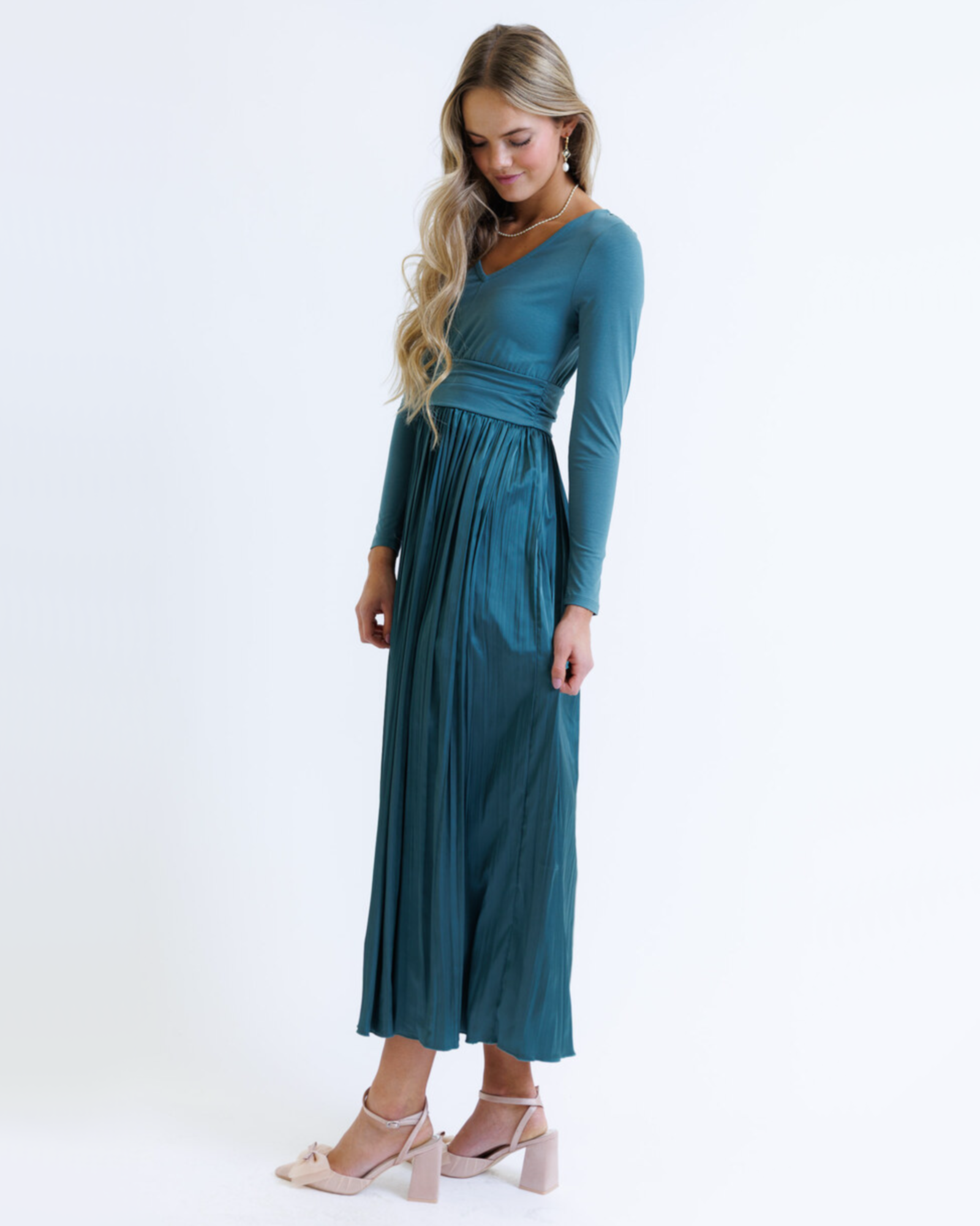 Woman wearing a teal long-sleeve dress on a white background