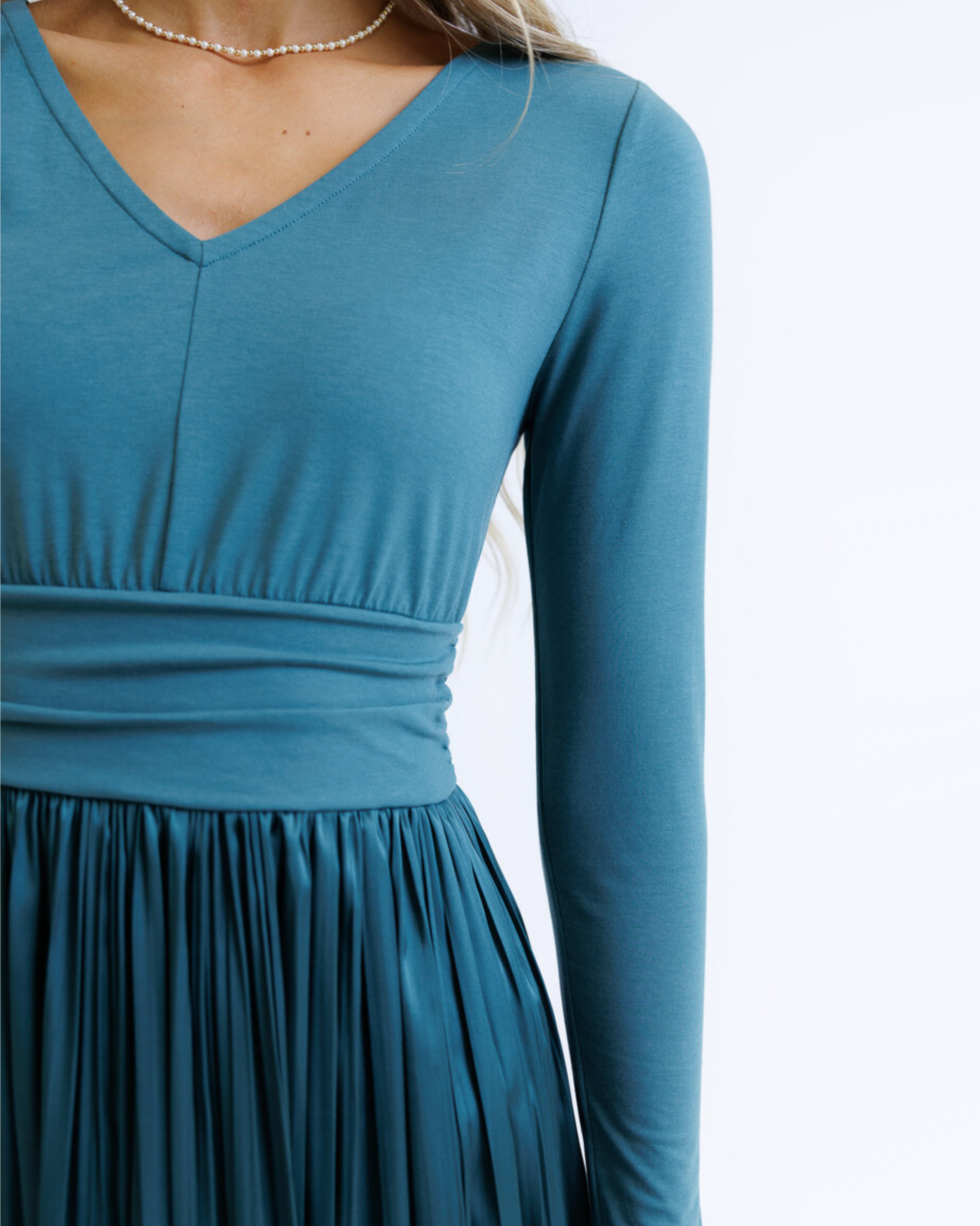Woman wearing a teal long-sleeve dress on a white background