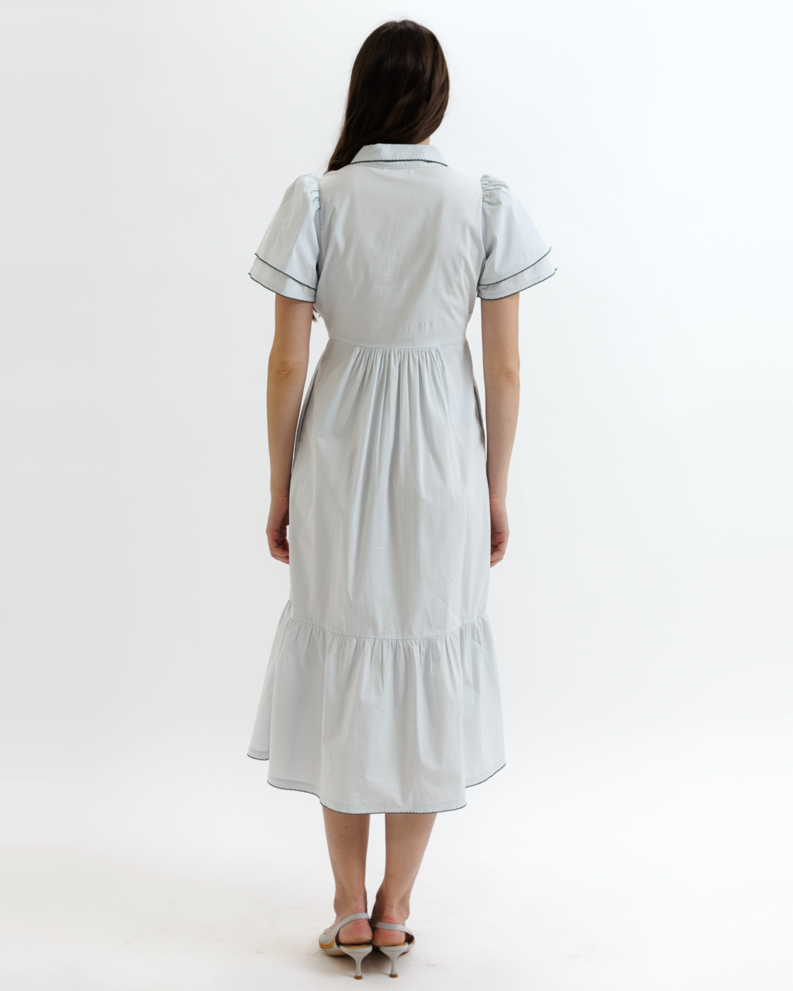 Woman wearing a light blue dress with black trim on a white background