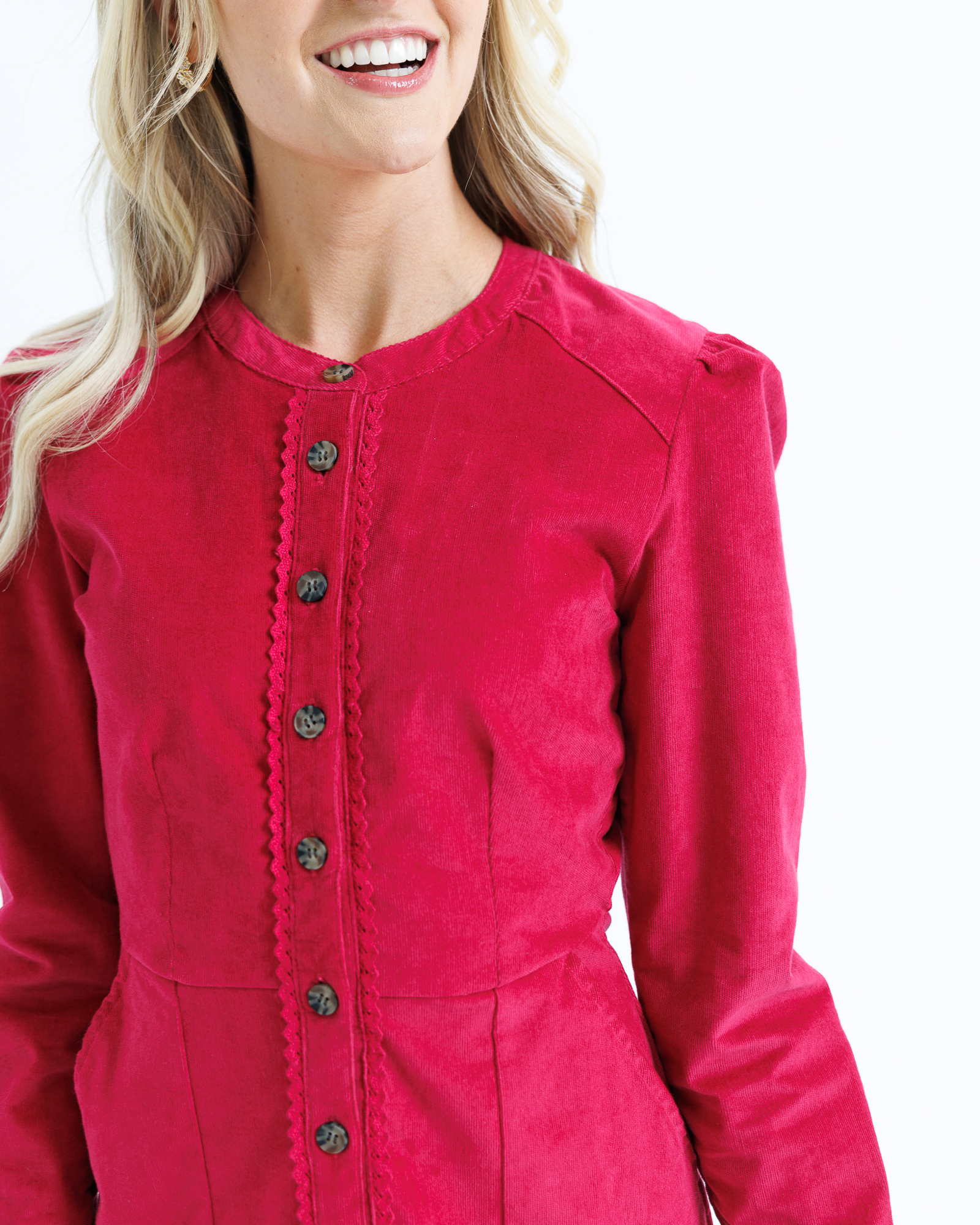 Red dress with black buttons worn by a woman on a white background