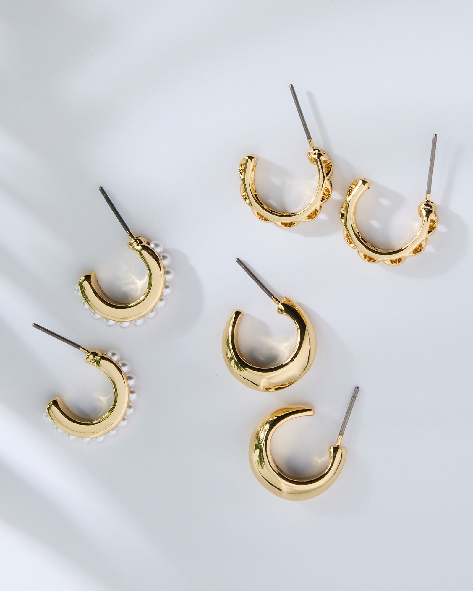 Set of gold hoop earrings on a white background
