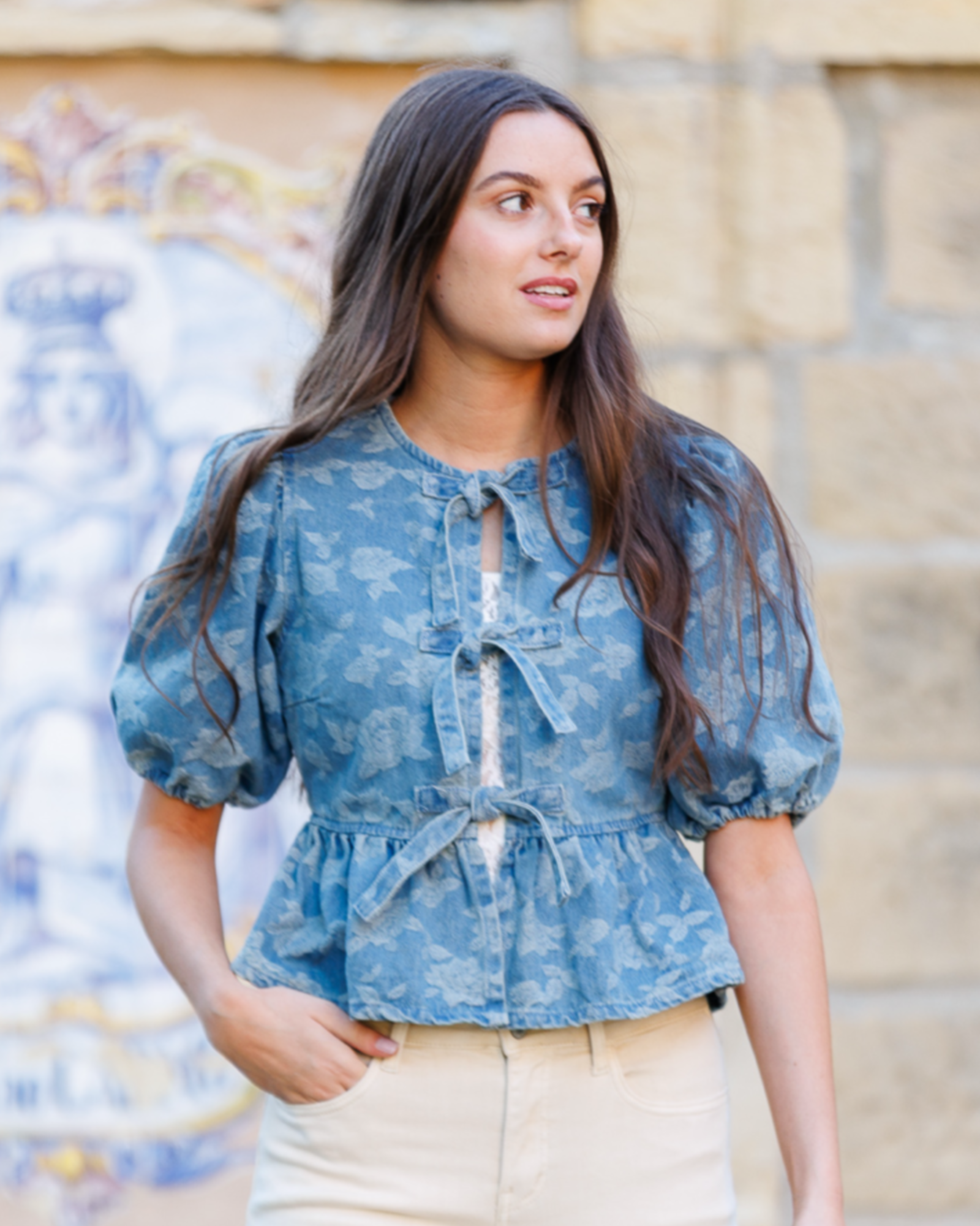 Woman wearing a blue denim floral blouse with a blurred background