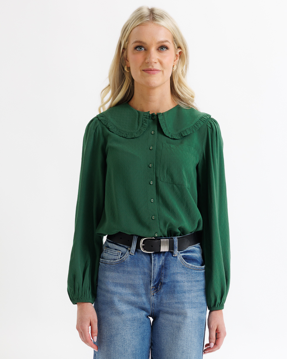 Woman wearing a green blouse and blue jeans on a white background