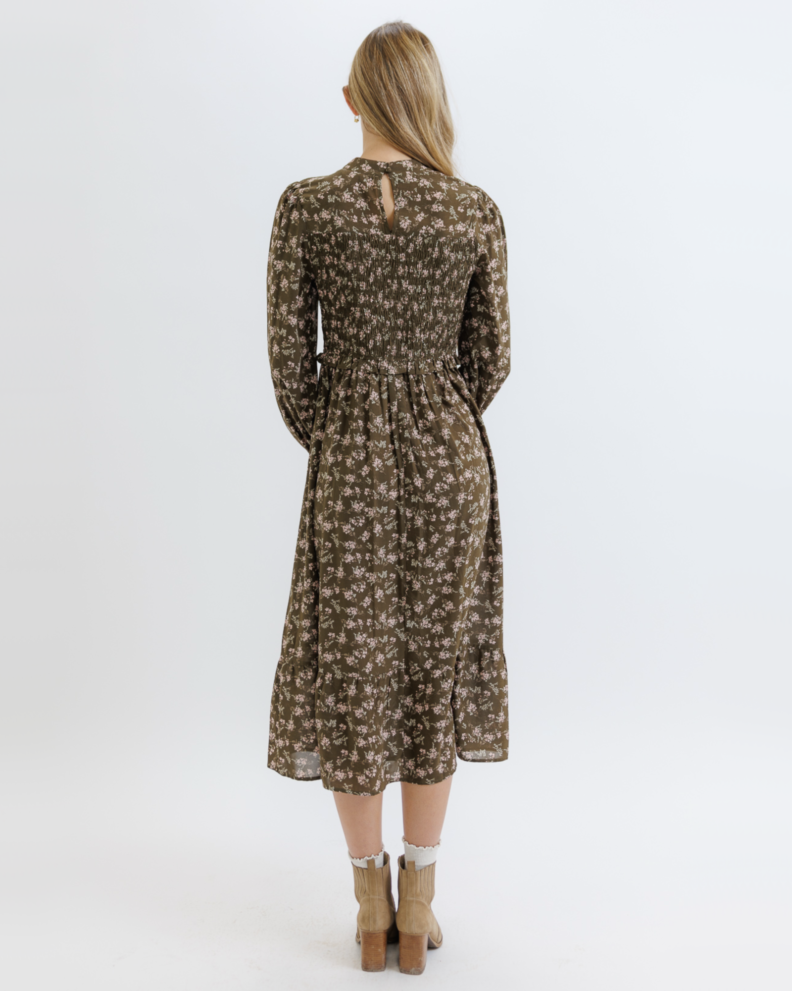 Woman wearing an olive green floral dress on a white background