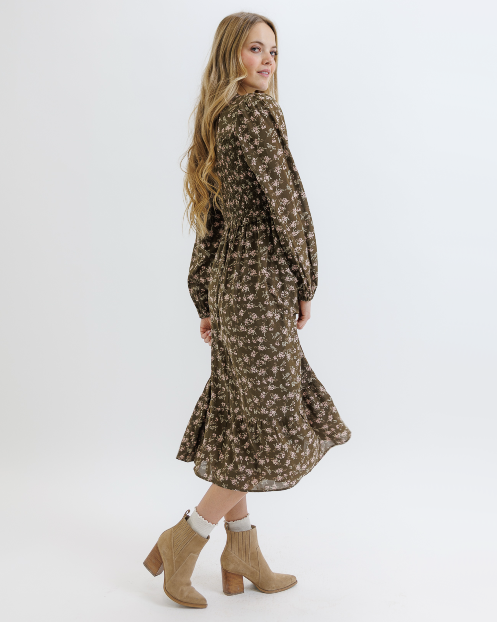 Woman wearing an olive green floral dress on a white background
