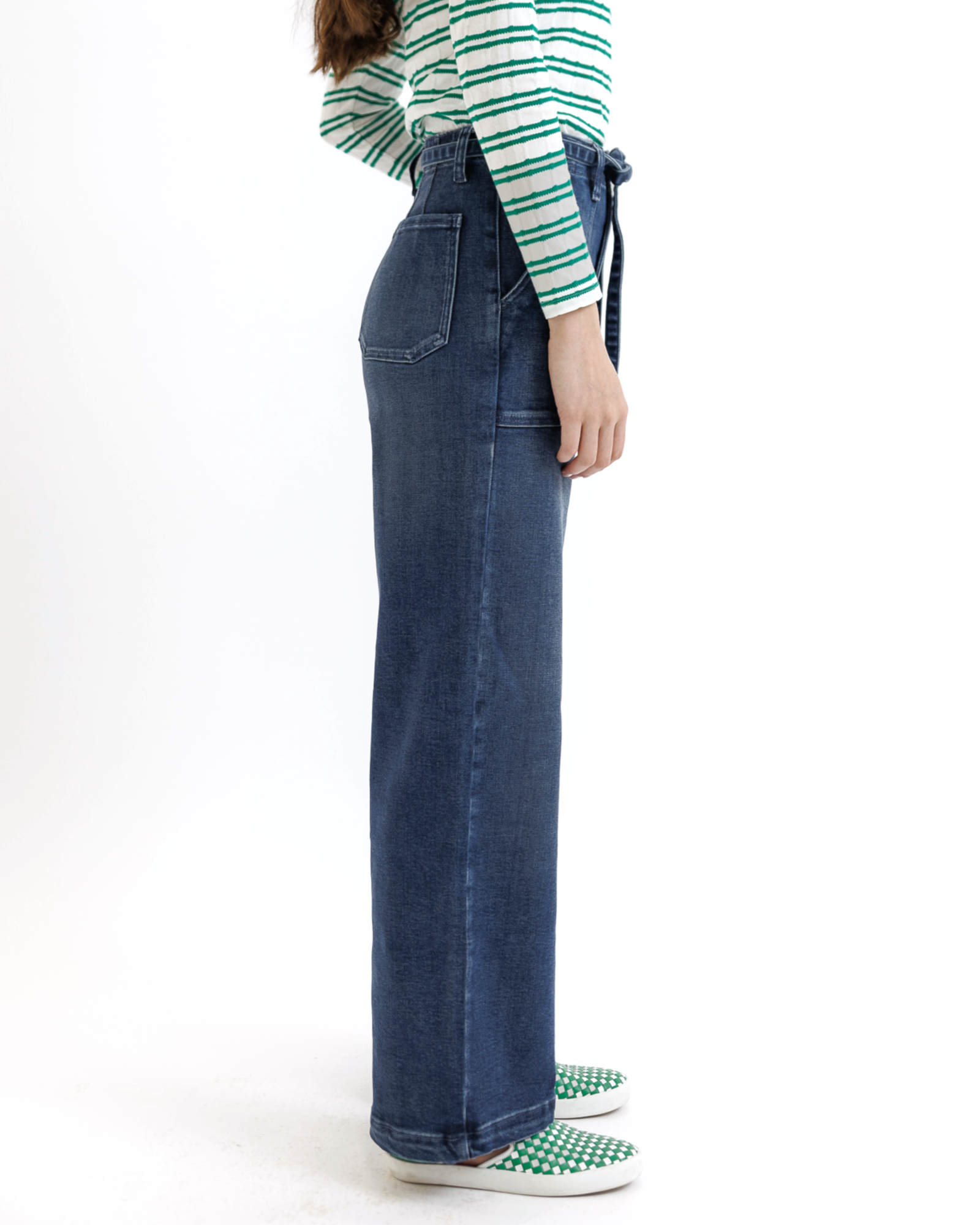 Woman wearing a green and white striped shirt and blue jeans on a white background