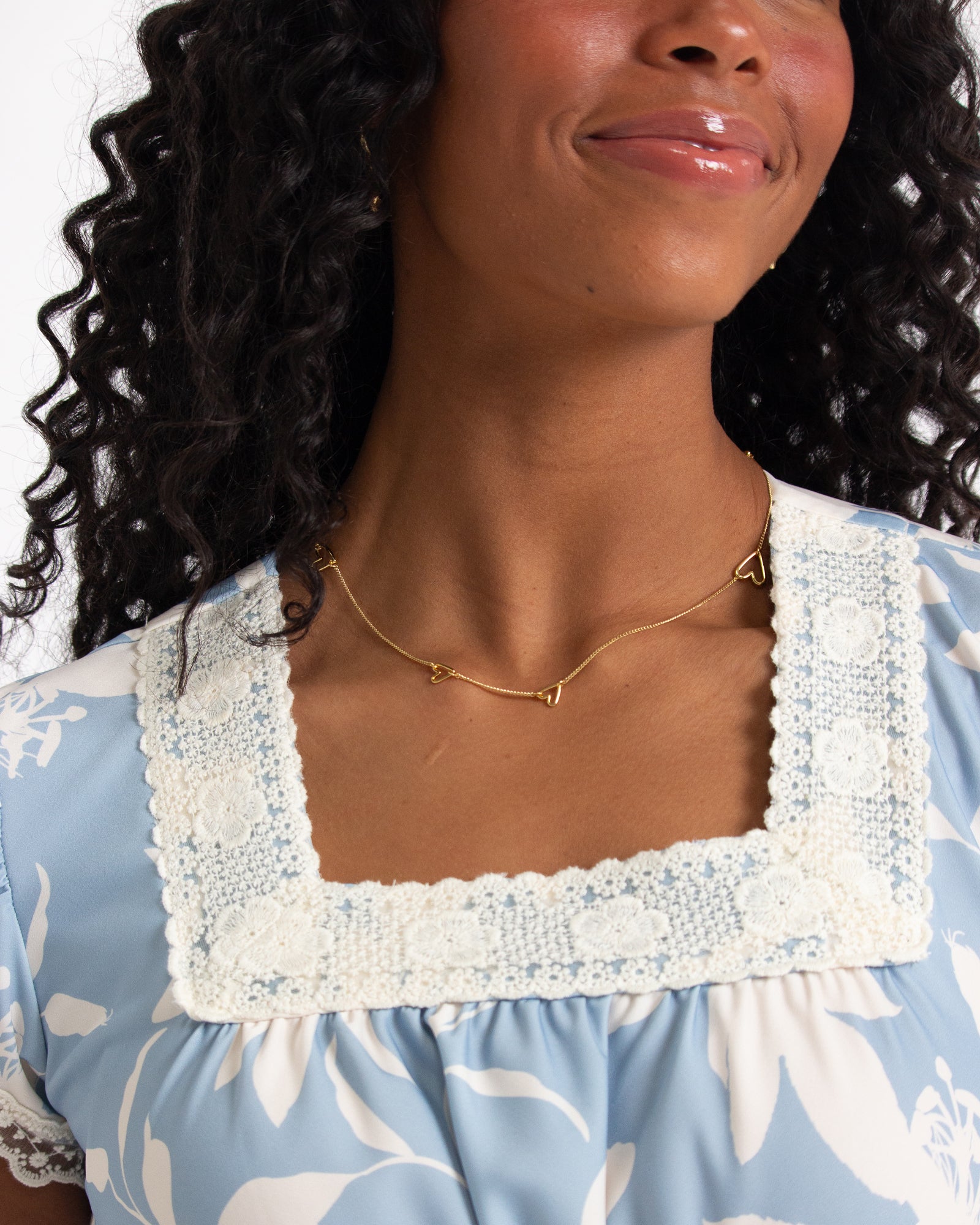 Woman wearing a blue floral dress with a white lace collar against a white background