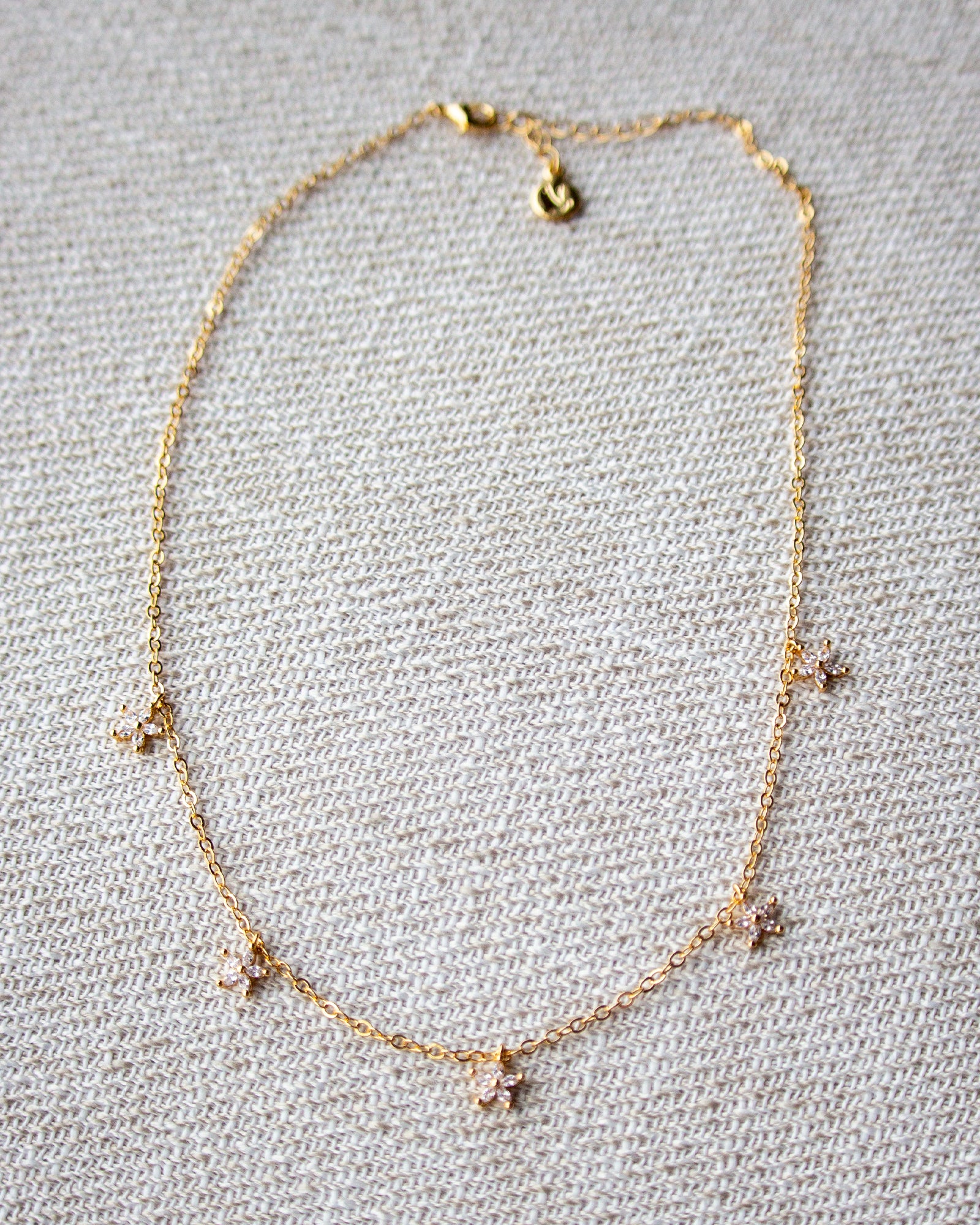 Gold necklace with small charms on a textured gray background