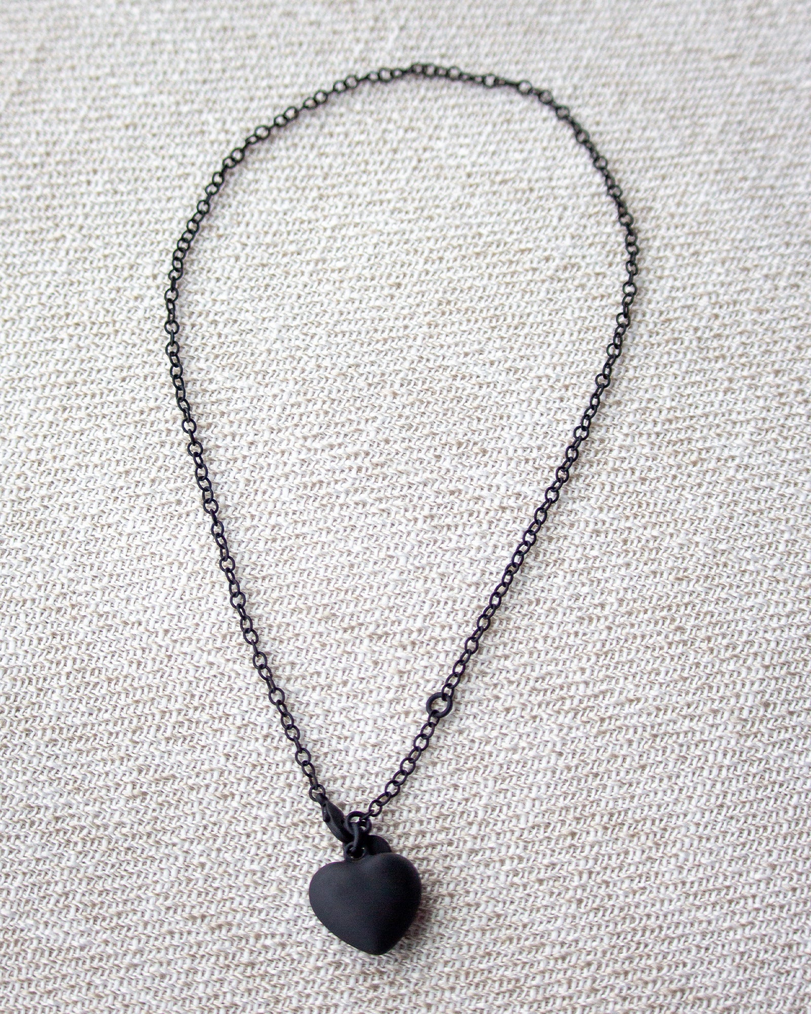 Black heart pendant necklace on a textured gray background
