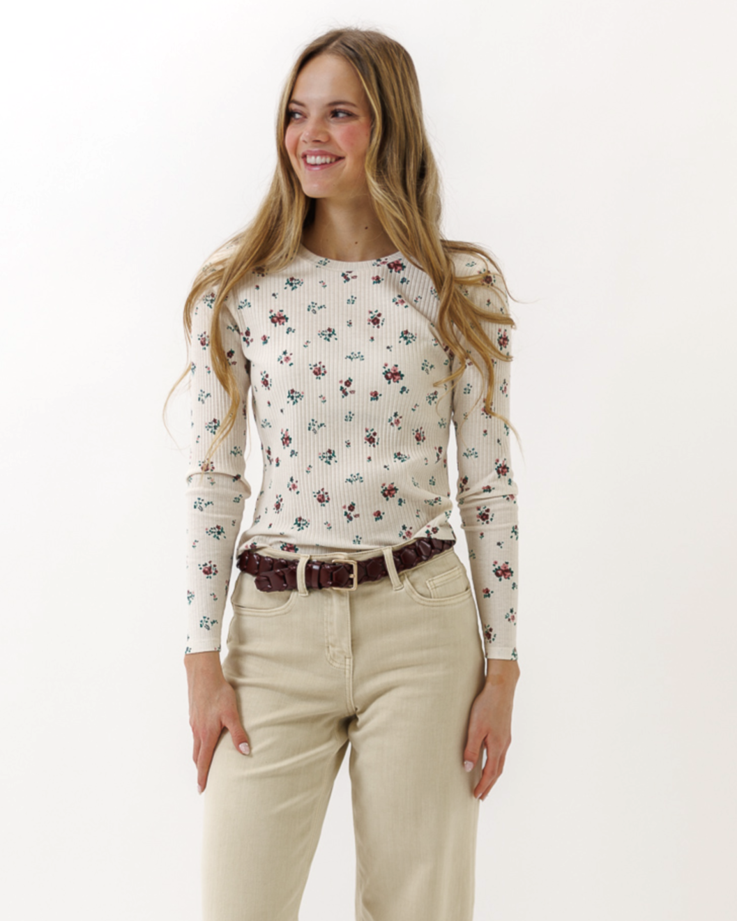 Woman wearing a floral top and beige pants on a white background