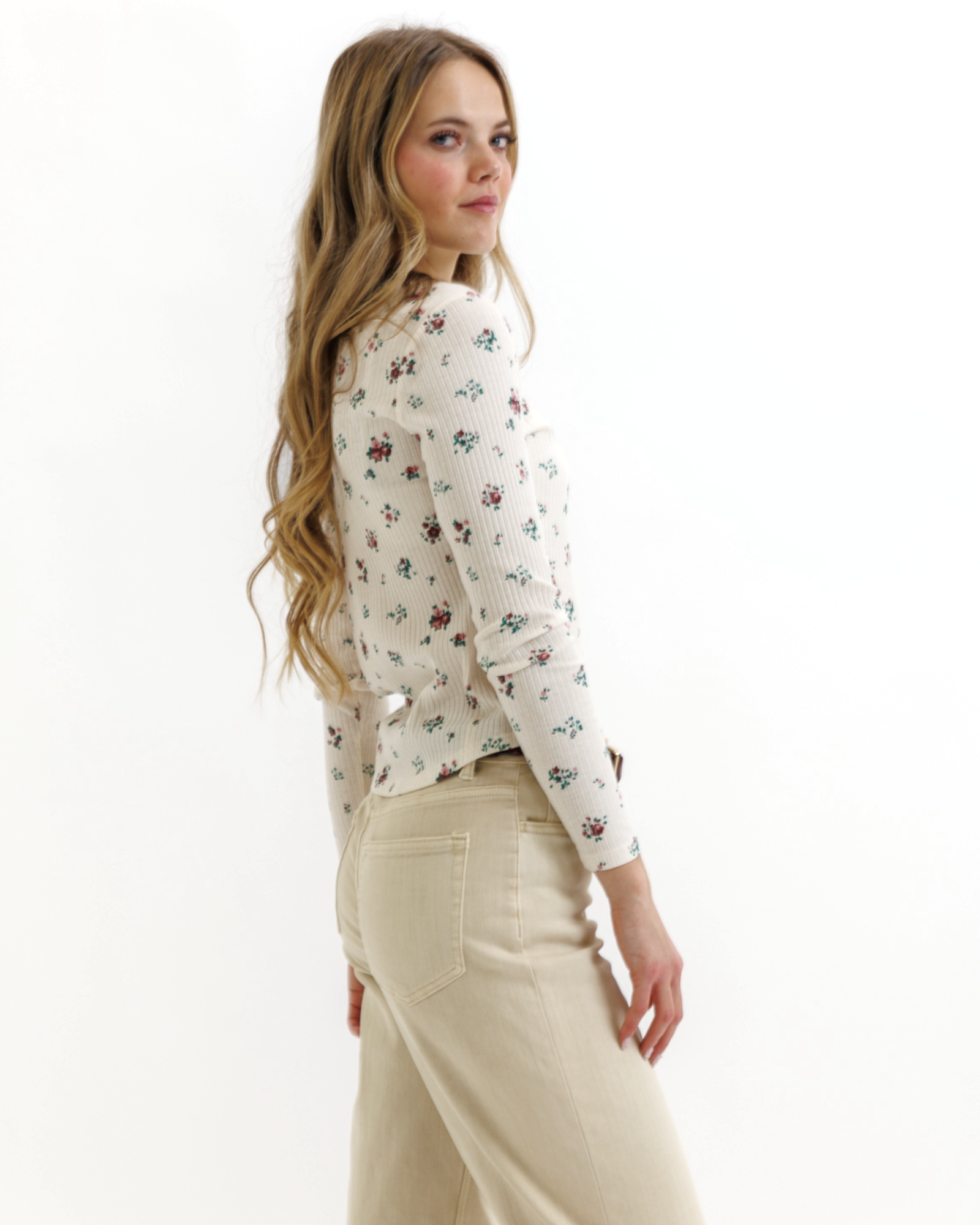 Woman wearing a floral top and beige pants on a white background