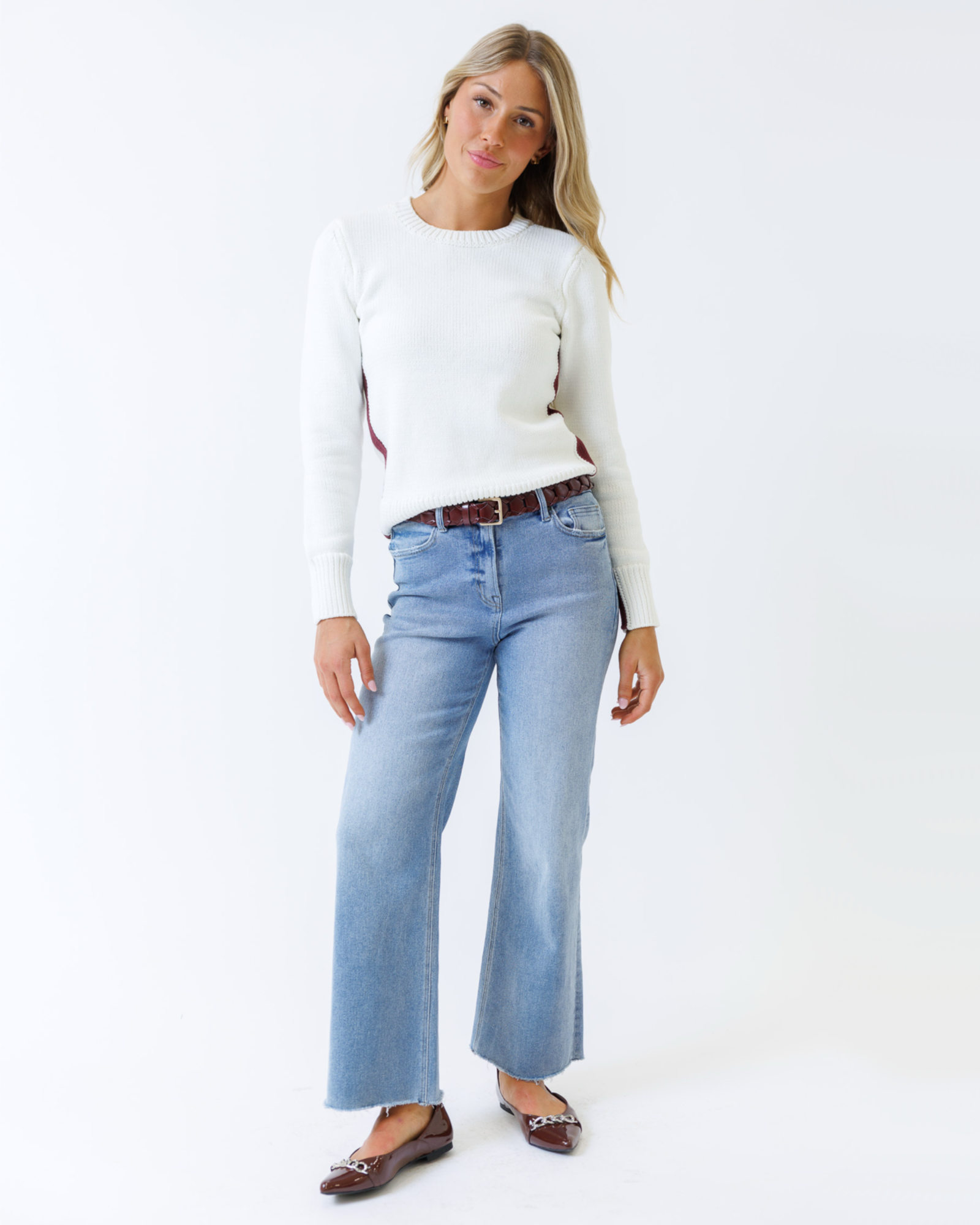 Woman wearing a white sweater and light blue jeans on a white background