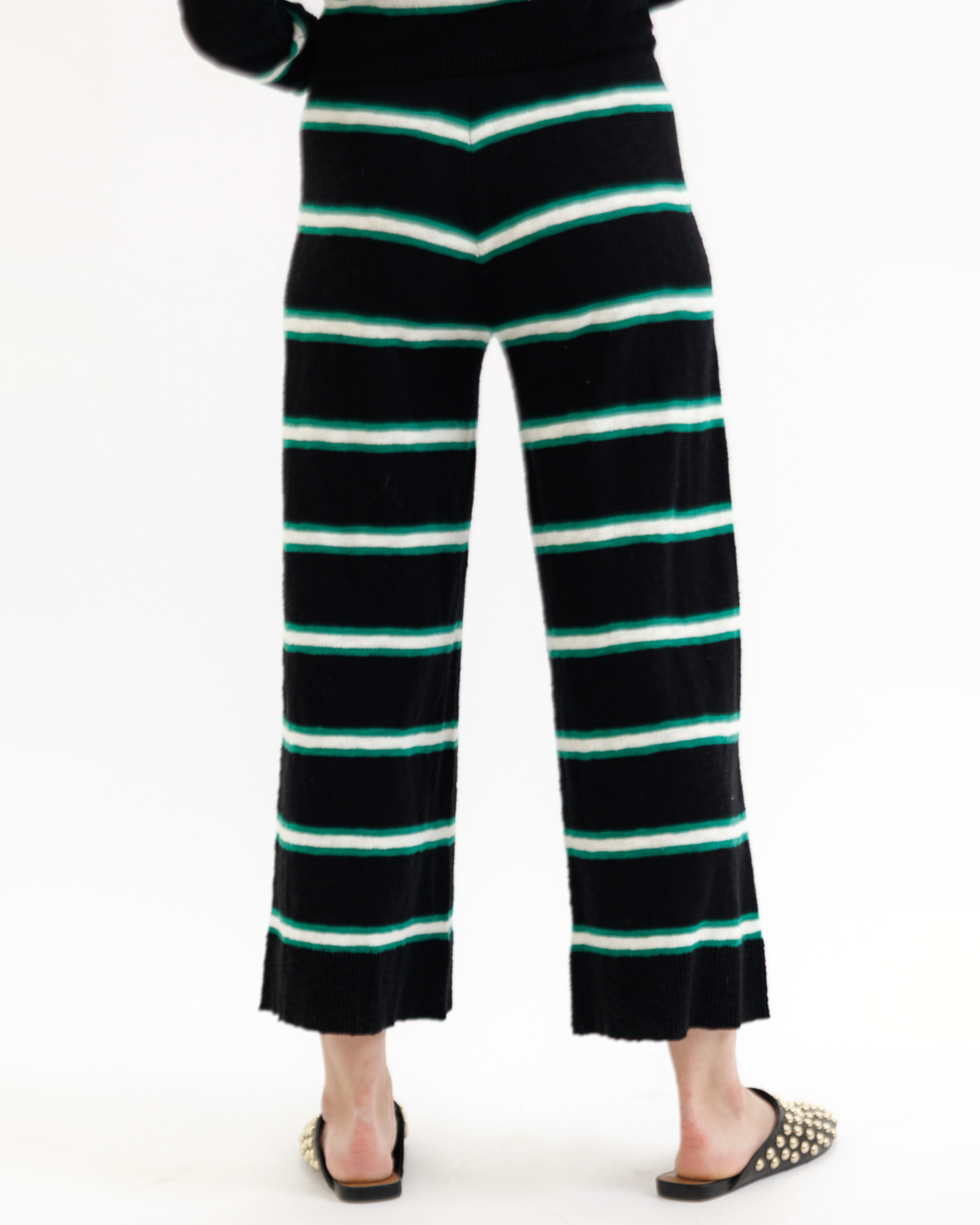 Woman wearing a black striped pants with green accents on a white background