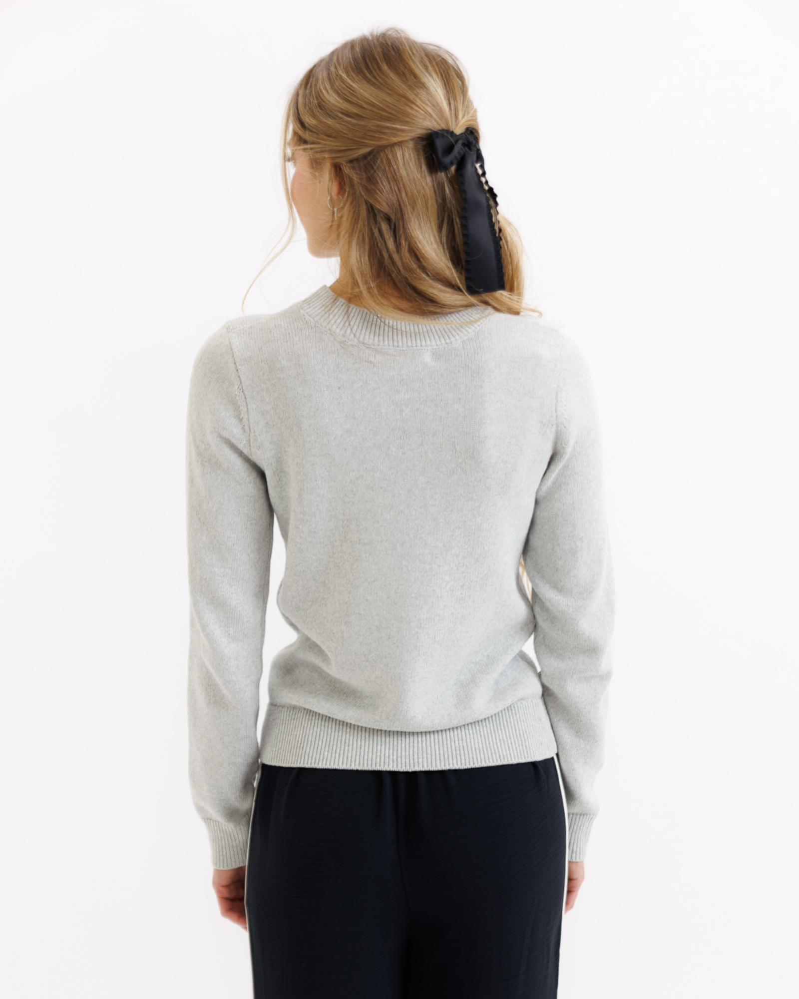 Woman wearing a gray sweater and black pants on a white background
