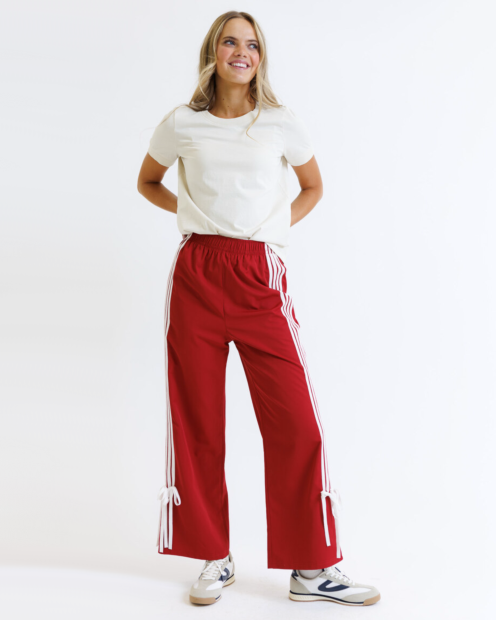 Woman wearing a white t-shirt and red pants with white stripes on a white background