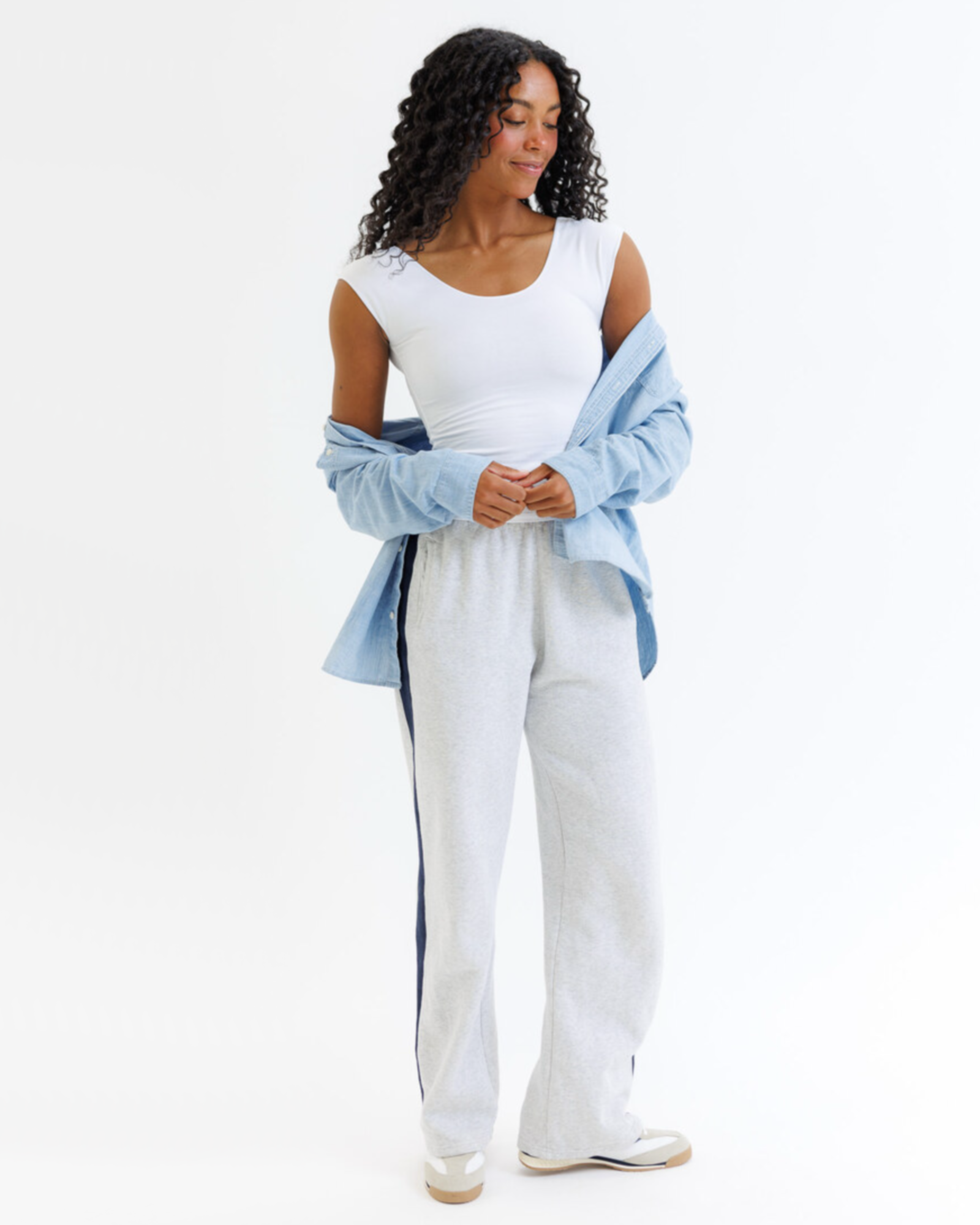Woman wearing a white layering top with a denim shirt on a white background