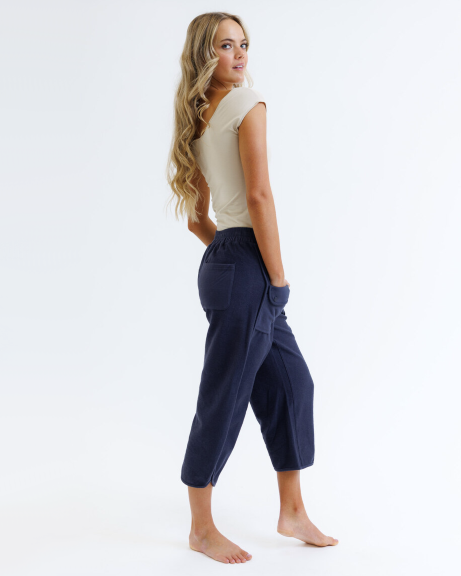 Woman wearing a beige top and navy blue pants on a white background
