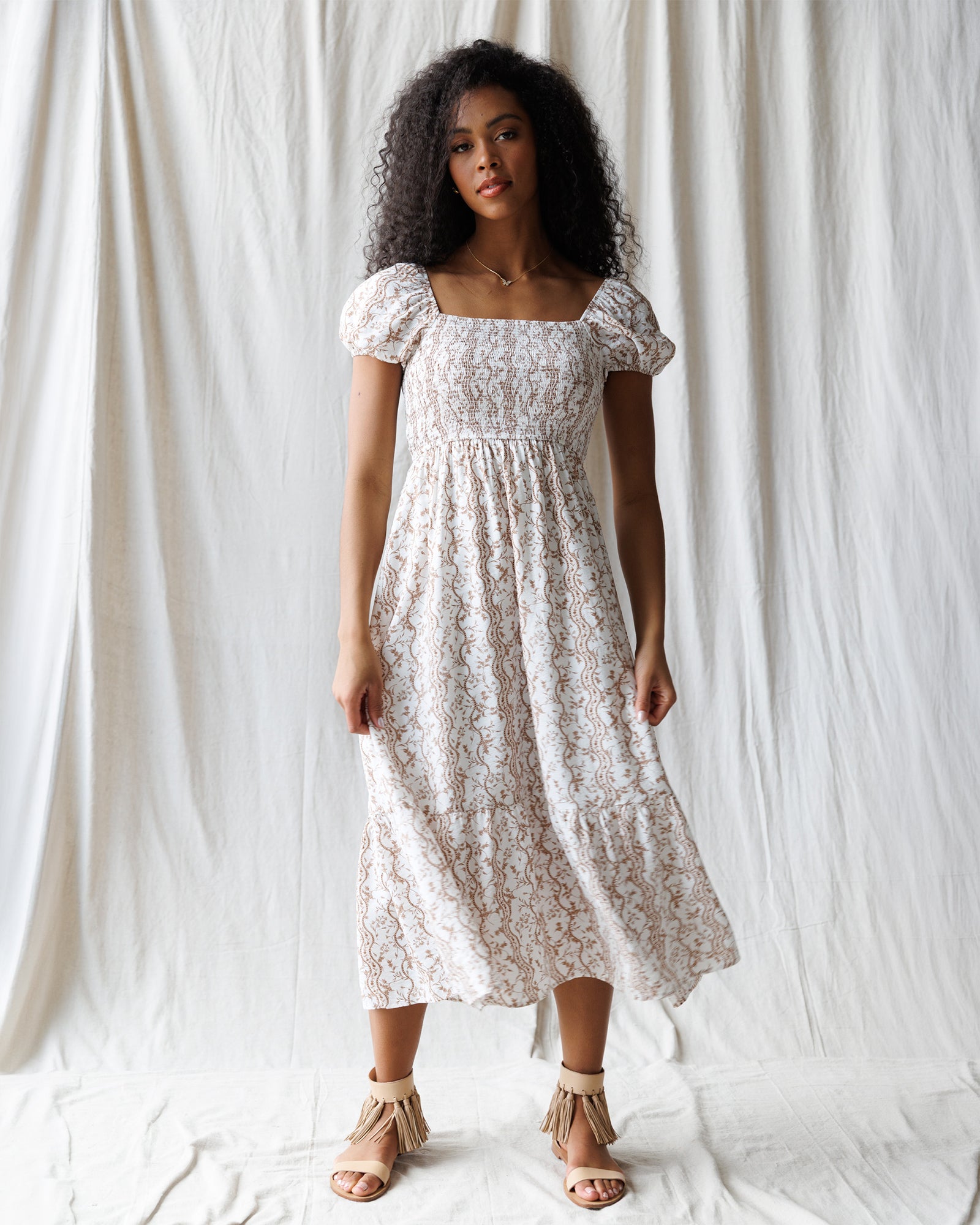 Woman wearing a white floral dress against a plain background