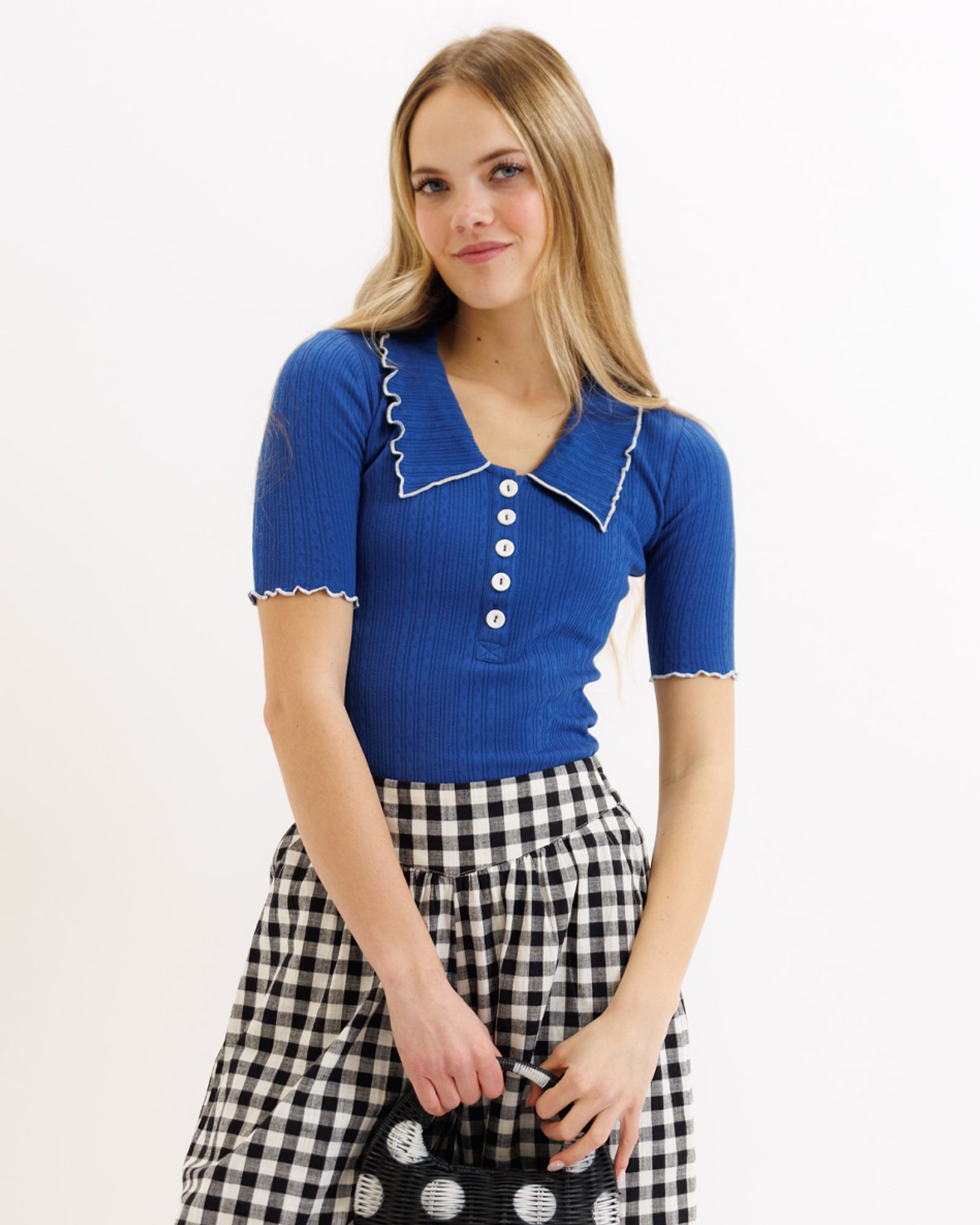 Woman wearing a blue top with white buttons and a checkered skirt on a white background