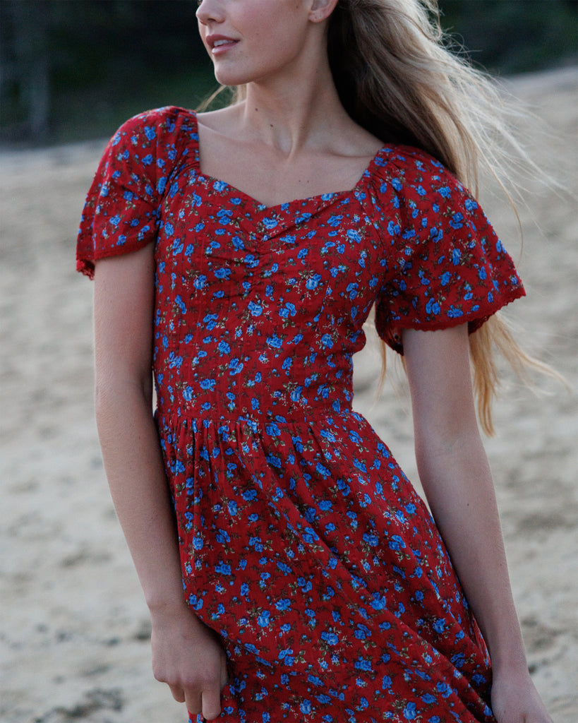 Woman wearing a red floral dress on a beach