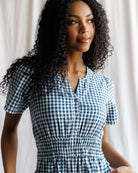 Woman wearing a blue and white checkered dress against a neutral background