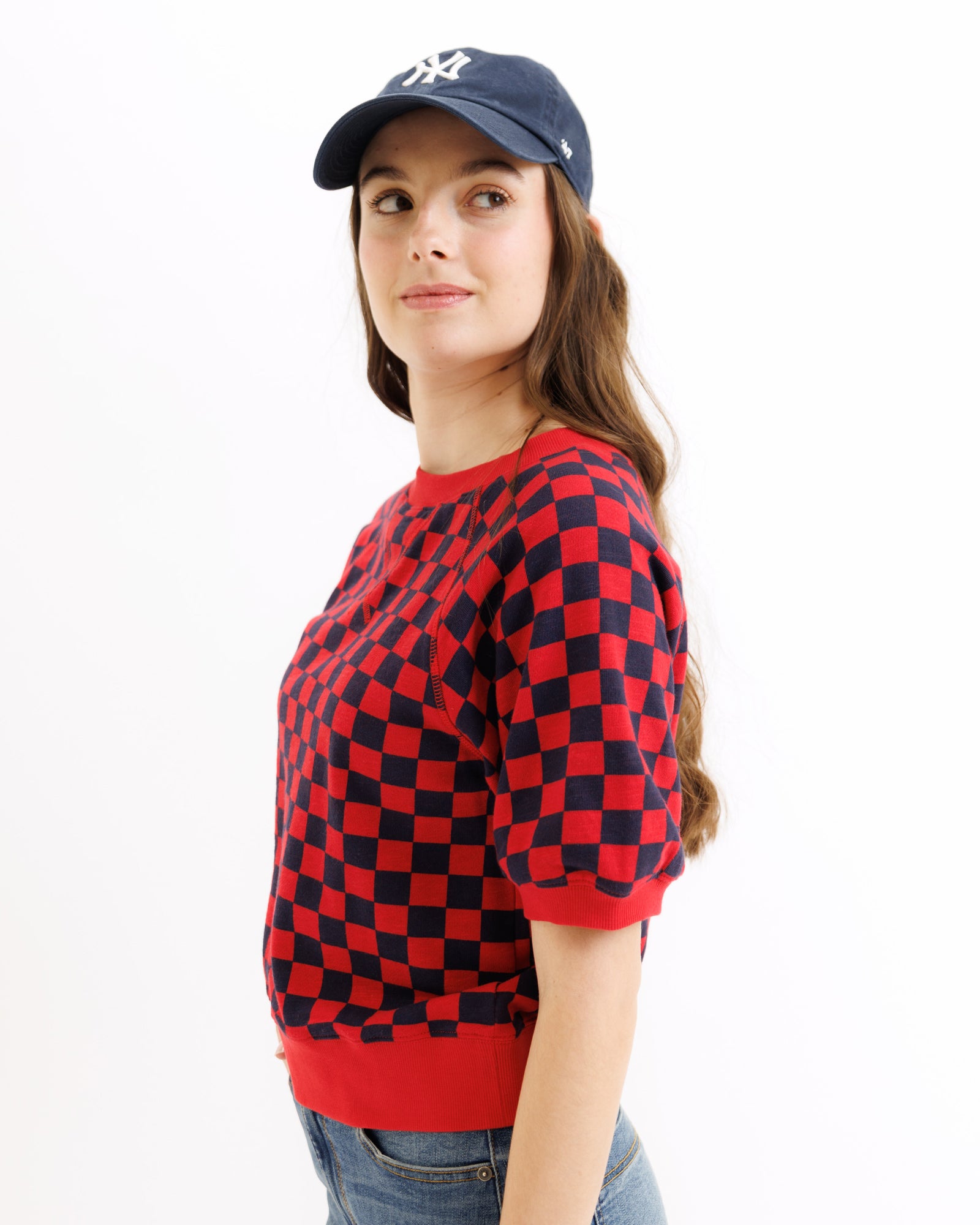 Person wearing a red and black checkered sweater with a blue cap on a white background