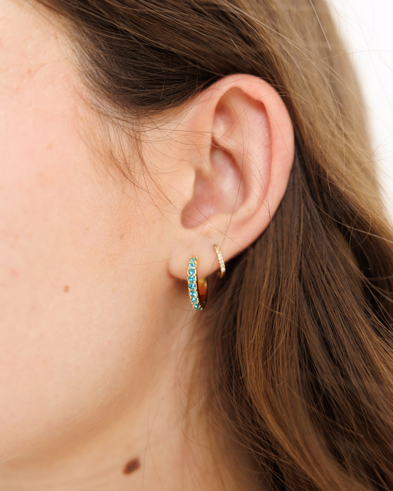 Close-up of an ear wearing two hoop earrings with a blurred background