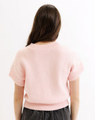Person wearing a light pink sweater on a white background