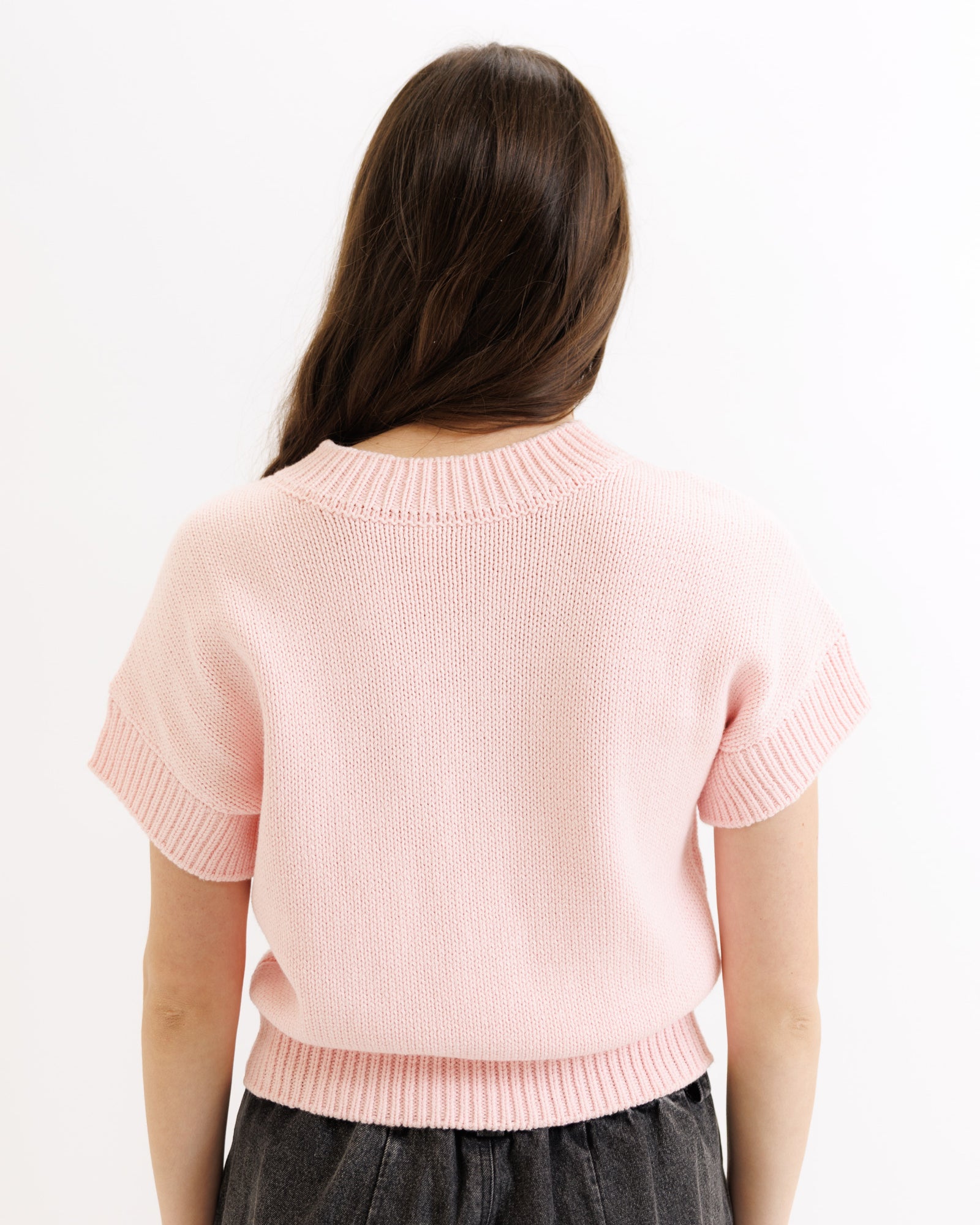 Person wearing a light pink sweater on a white background