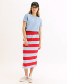 Woman wearing a light blue t-shirt and red and white striped skirt on a white background
