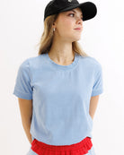 Woman wearing a light blue t-shirt and red shorts with a black cap on a white background