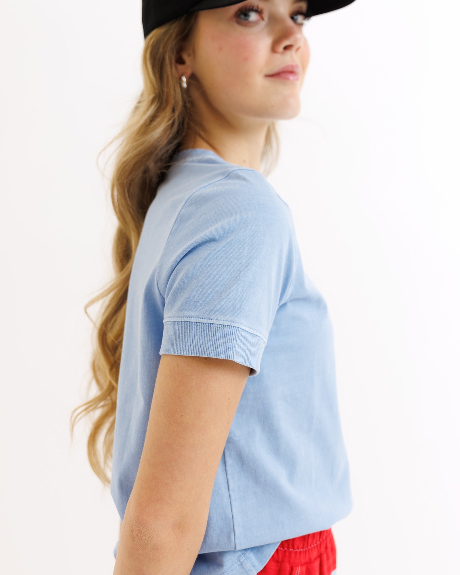 Person wearing a light blue t-shirt and red shorts on a white background