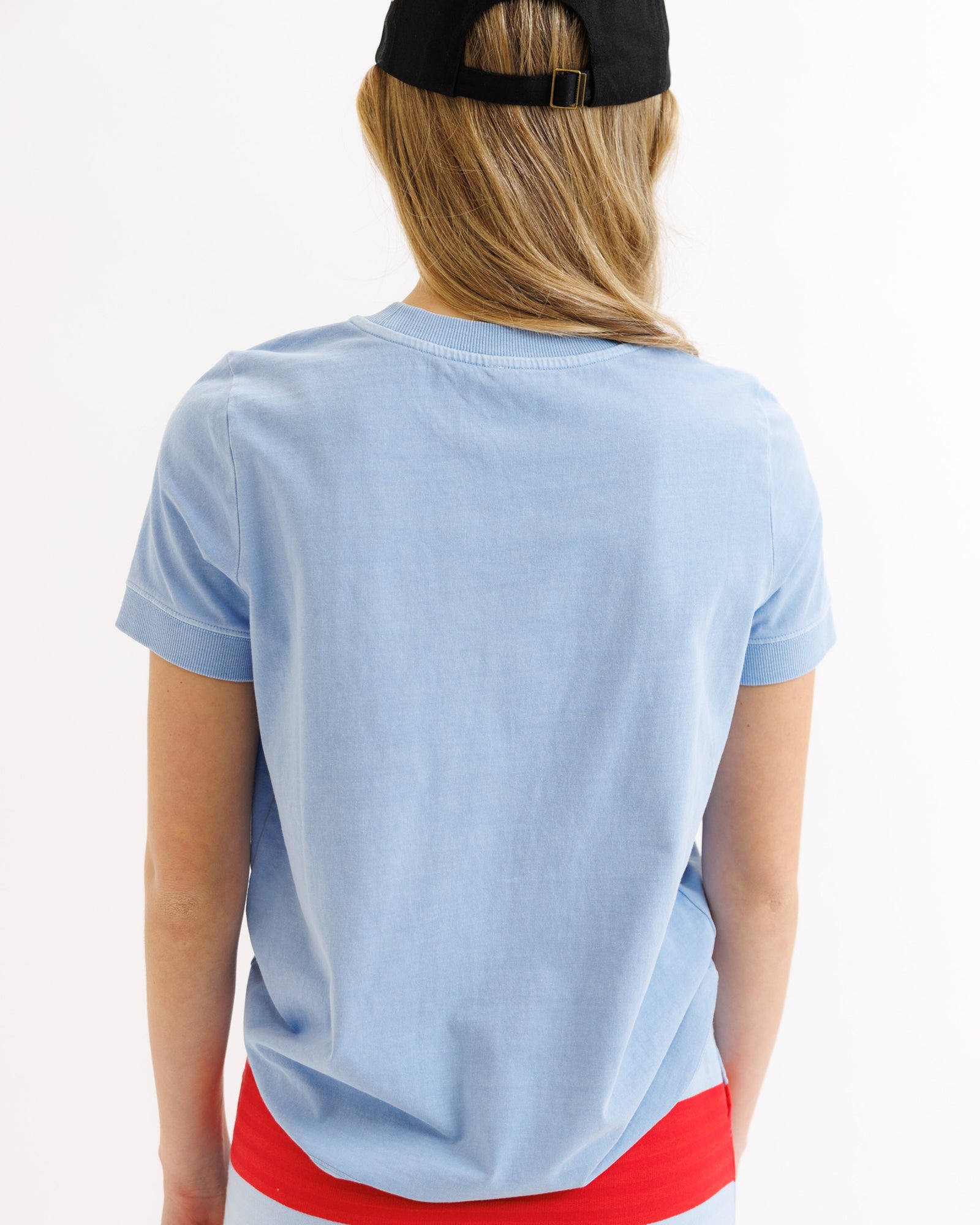 Person wearing a light blue t-shirt with a red bottom section on a white background