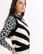 Woman wearing a black and white striped sweater with patterned sleeves on a white background