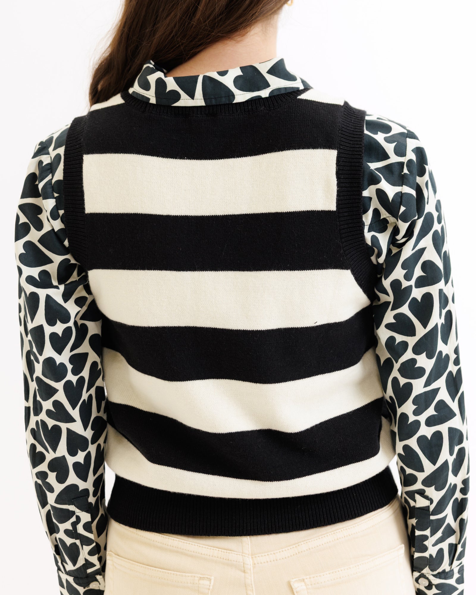 Black and white striped sweater with patterned sleeves on a plain background