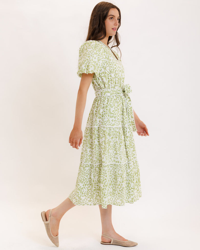 Model wearing a green printed short sleeve v-neck midi dress with a tie at the waist