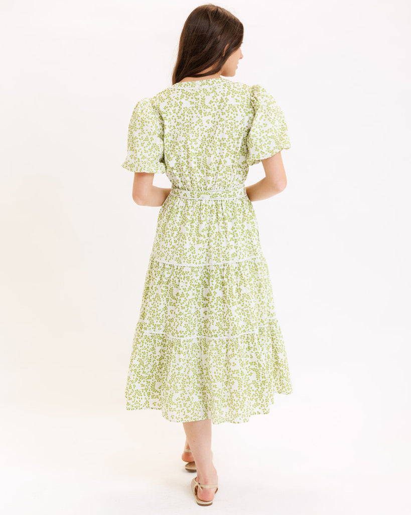 Model wearing a green printed short sleeve v-neck midi dress with a tie at the waist