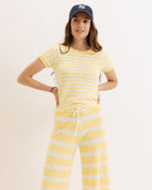 Woman wearing yellow and white striped pajamas with a blue cap on a white background