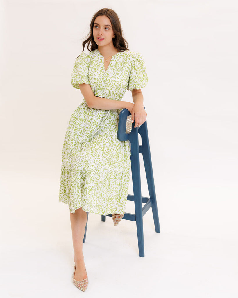 Model wearing a green printed short sleeve v-neck midi dress with a tie at the waist