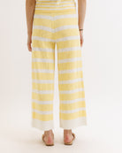 Yellow and white striped pants worn by a person on a light pink background
